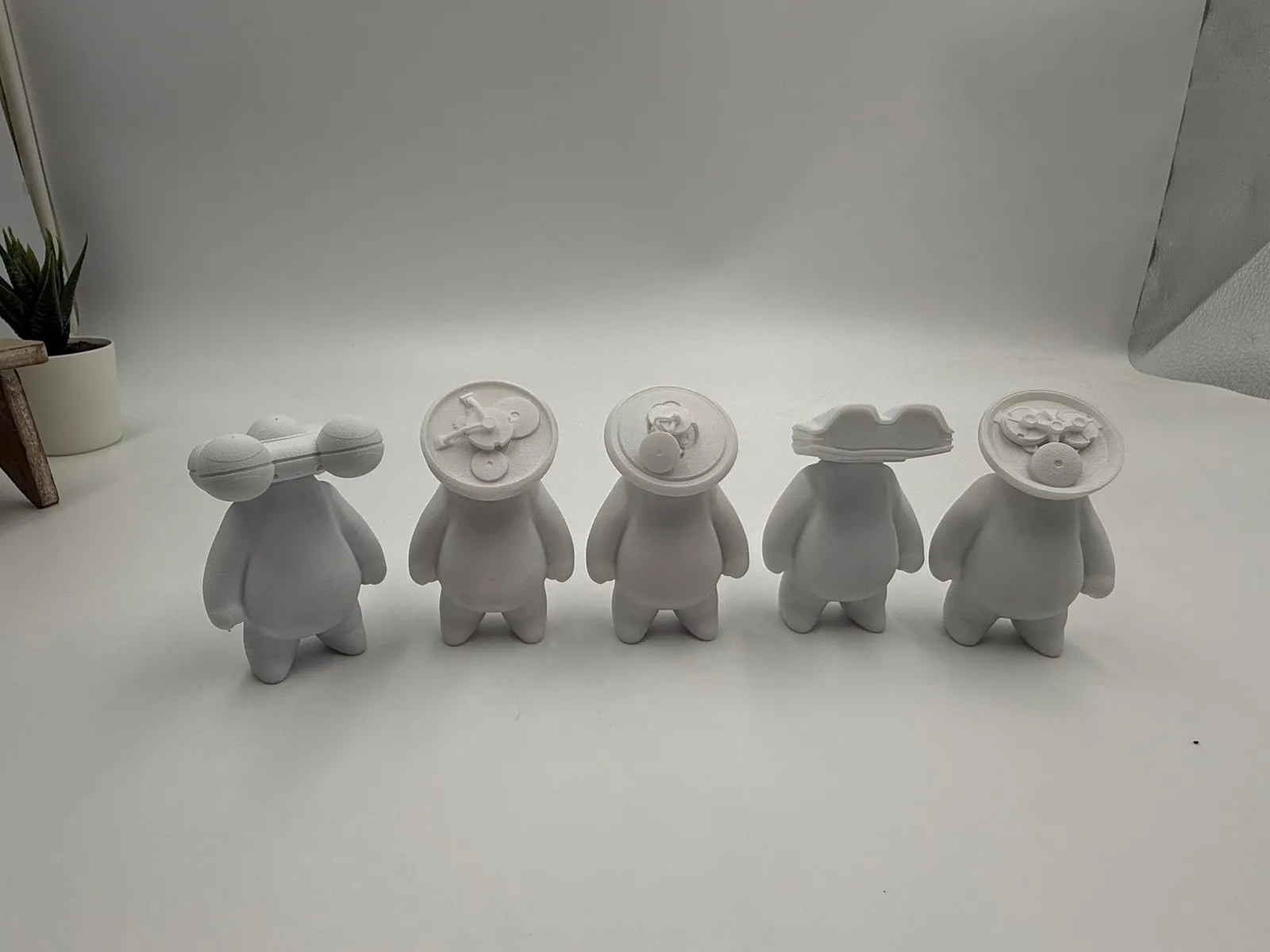 Five white Minimilian figures in a row, each a different design, printed with a textured skin