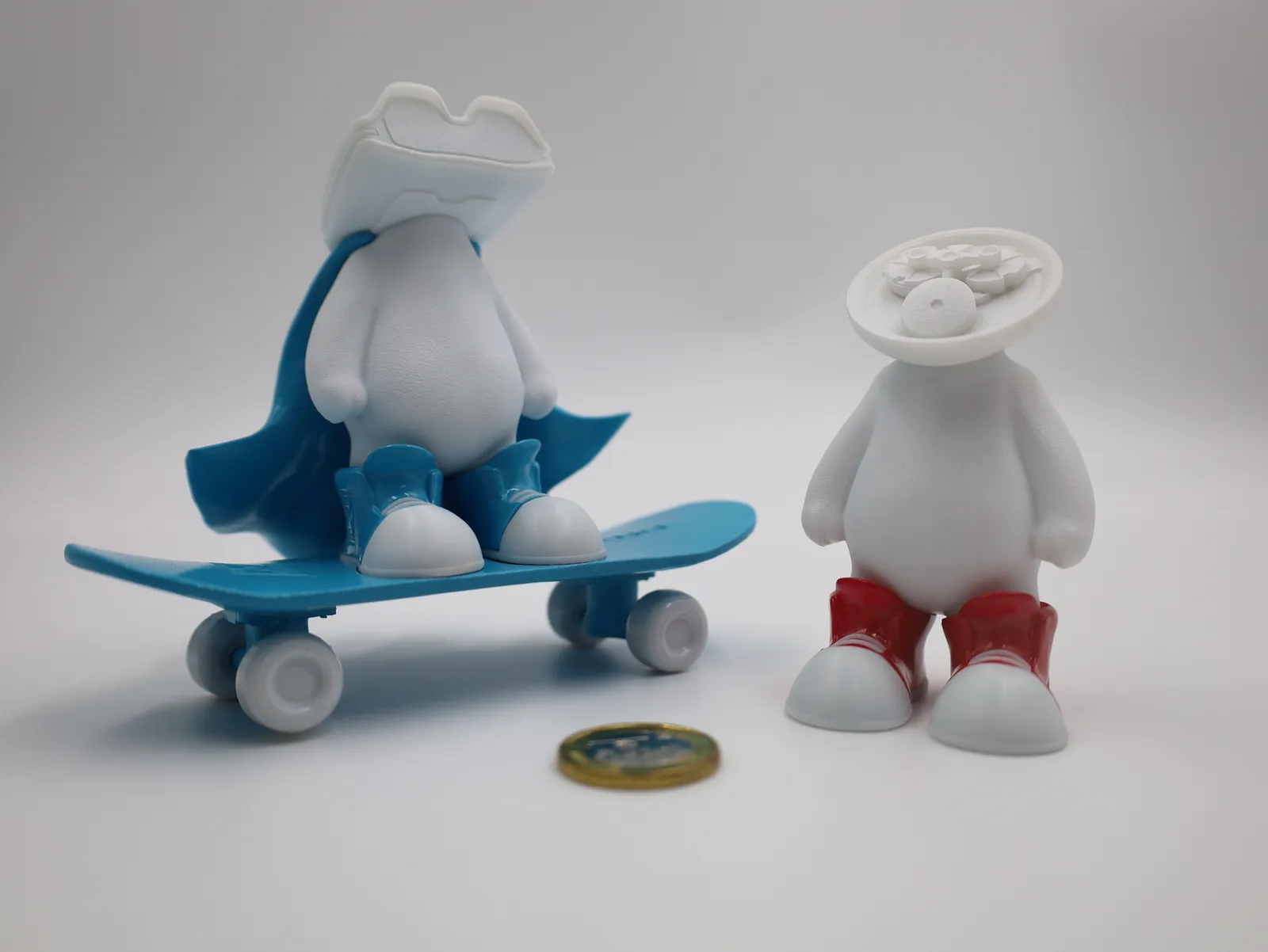 Two painted samples: a figure in a blue cape and shoes on a blue skateboard, beside a figure in red shoes