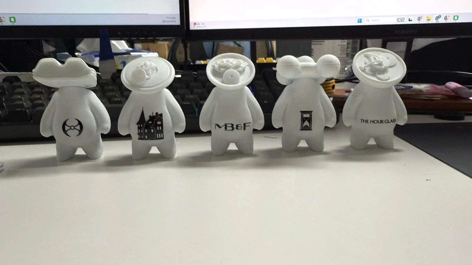 Five white figures in a row, each with a black logo icon on its belly for AR camera scanning