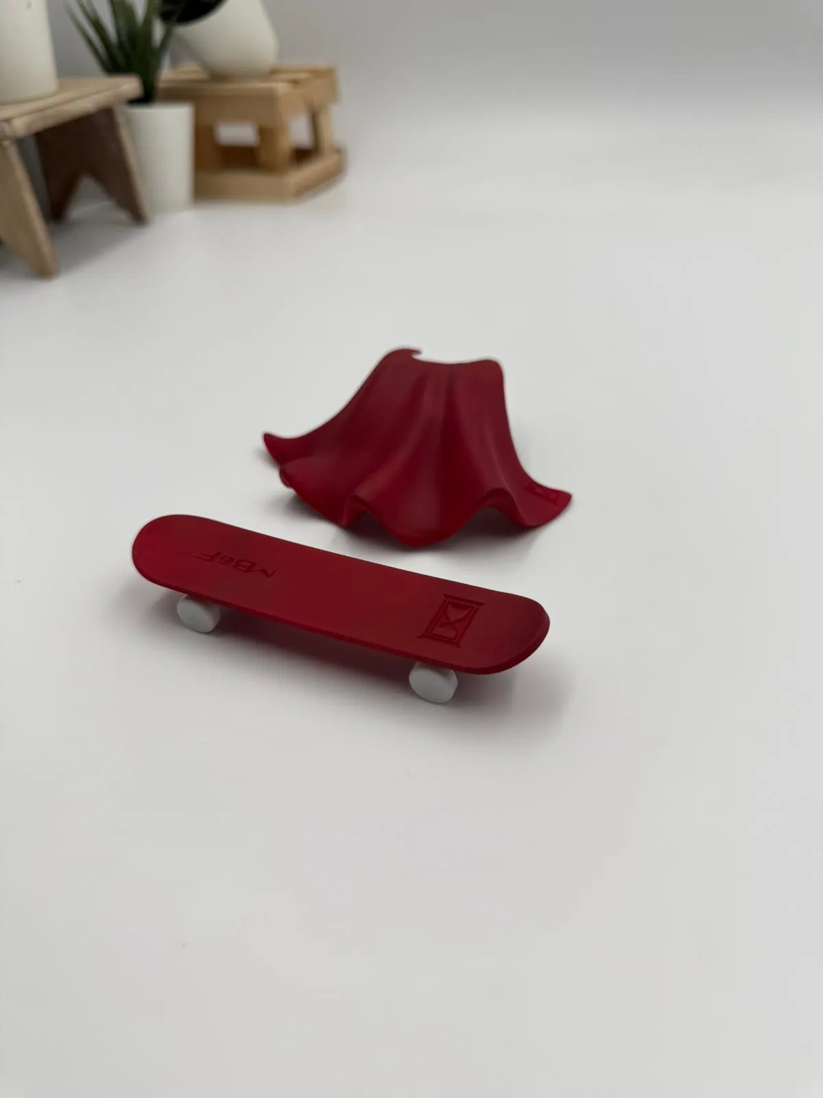 A red cape and a red skateboard with silver grey wheels, sprayed as a colour trial