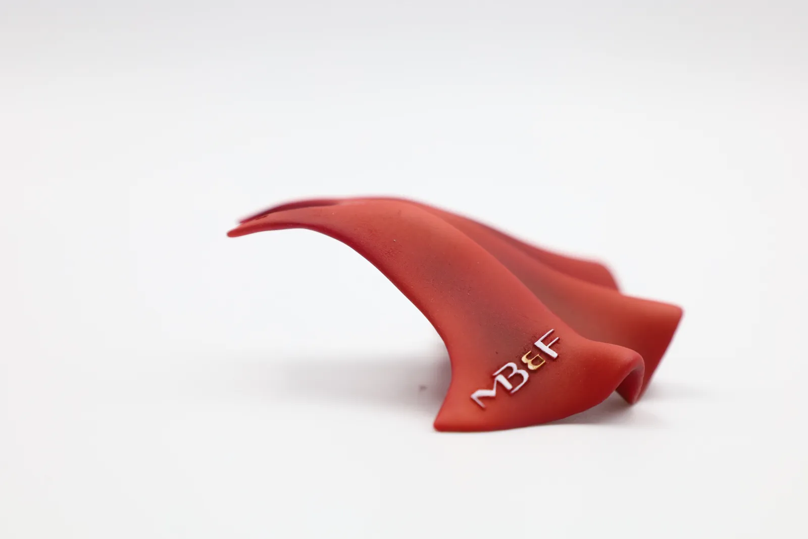 A finished red cape from the other side, with the MB&F logo debossed near its lower edge
