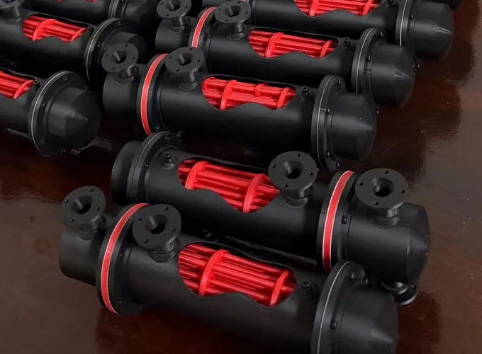 Close-up of two heat exchanger models: black shells with flanged nozzles and red rings, cut open to show the red tube bundle
