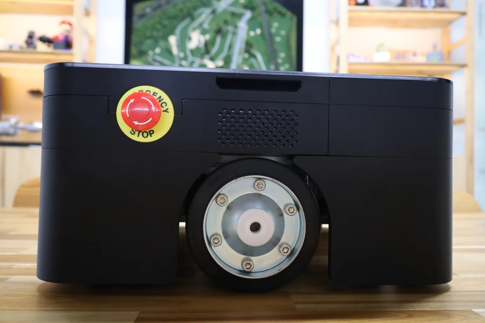 Side view of the covered AGV: the emergency stop button, the speaker grille beside it and the skirt shaped around the drive wheel