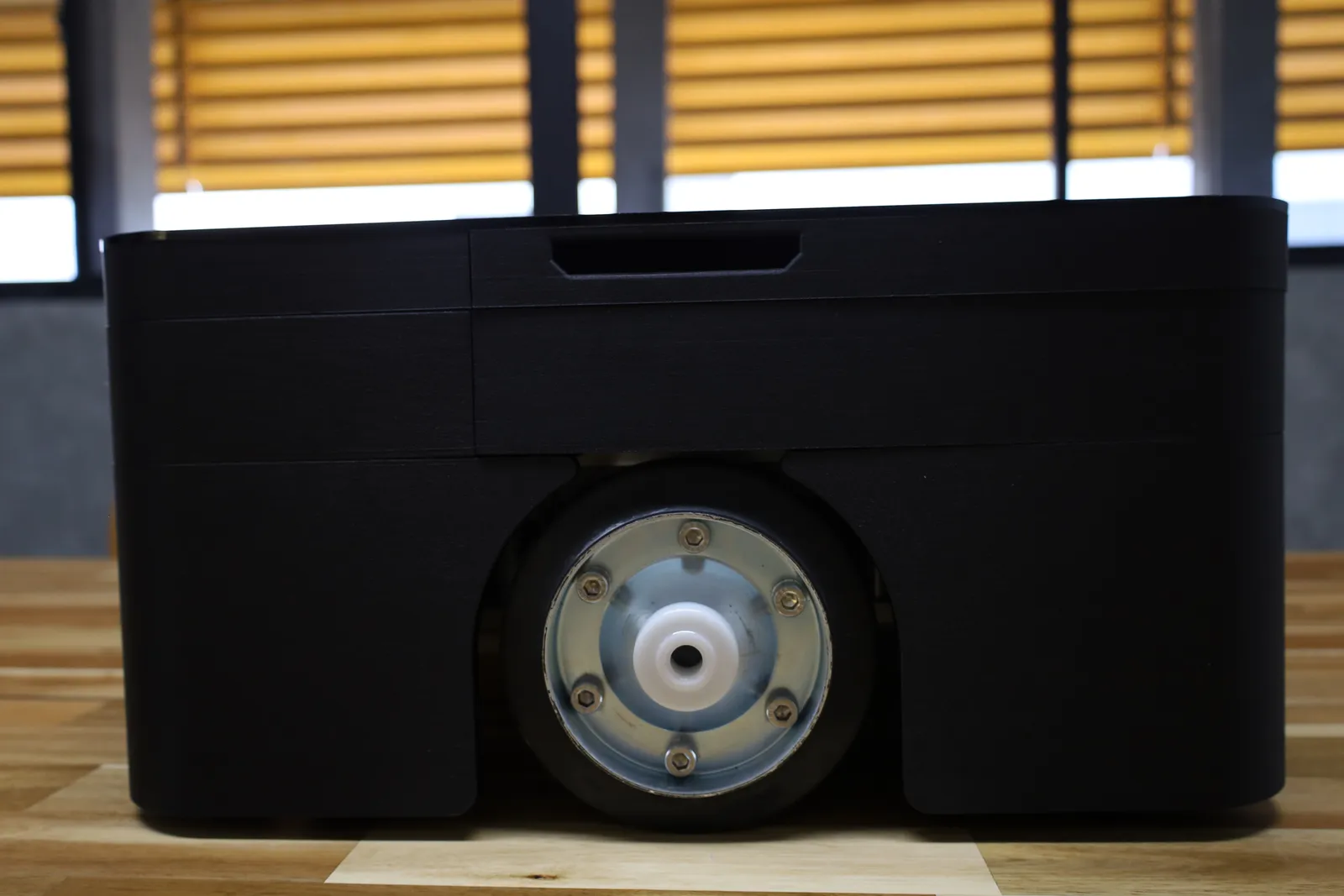 The side without the emergency stop: the drive wheel framed by the skirt and the hand grip cut into the top shell