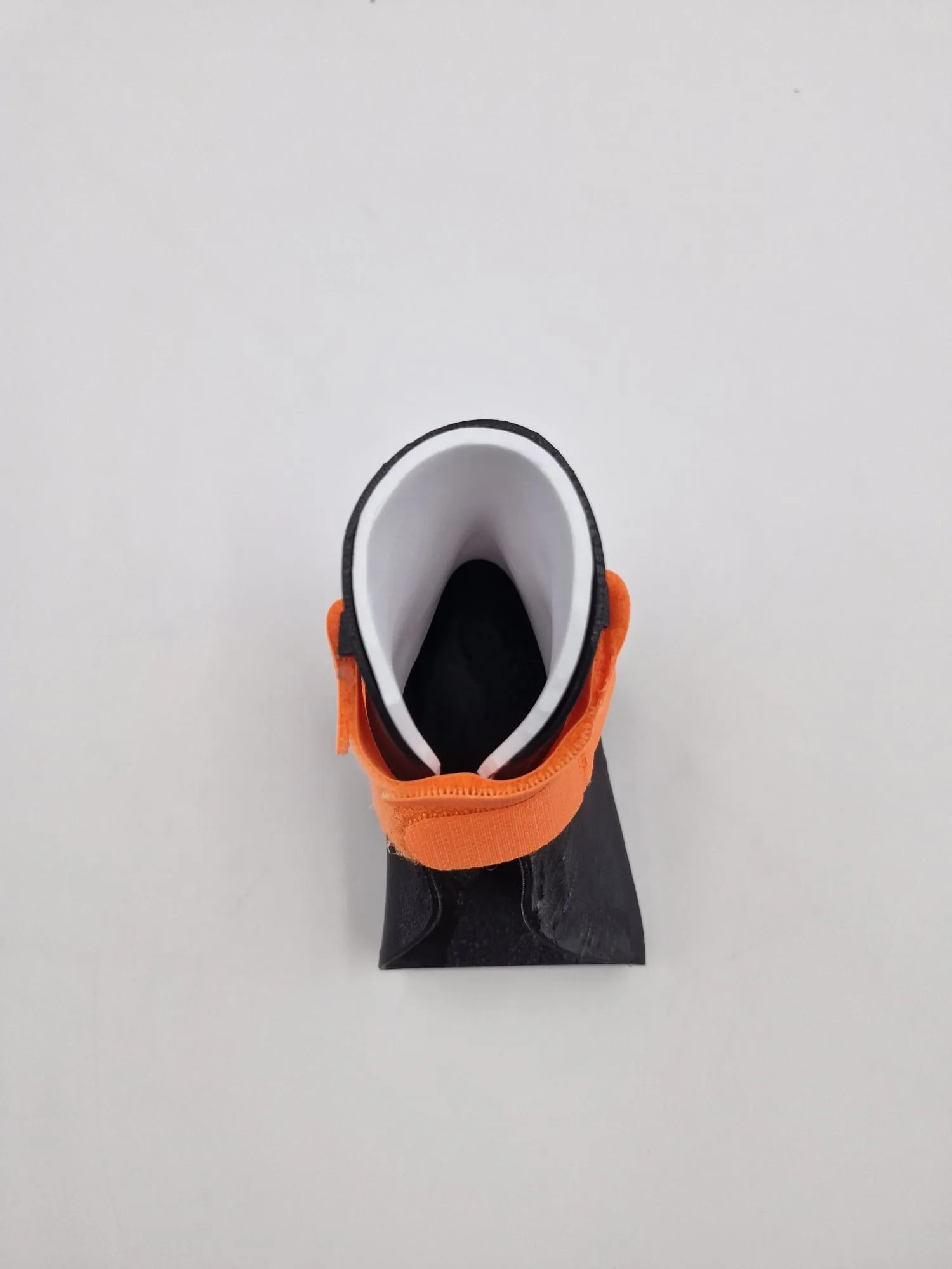 The test brace seen from the toe end, with the white foam lining inside the black TPU cuff and an orange strap across the front