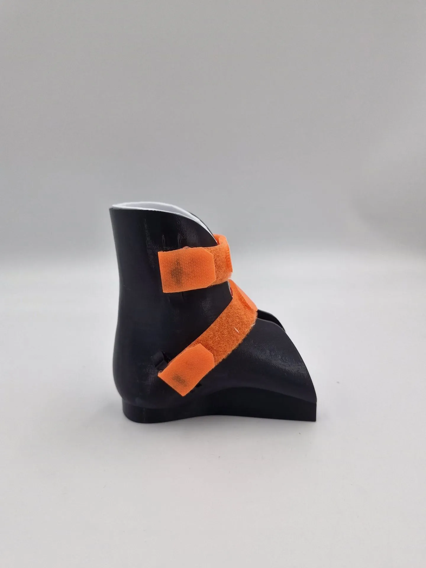 The strapped brace from its other side, with the two orange straps crossing the ankle and the instep
