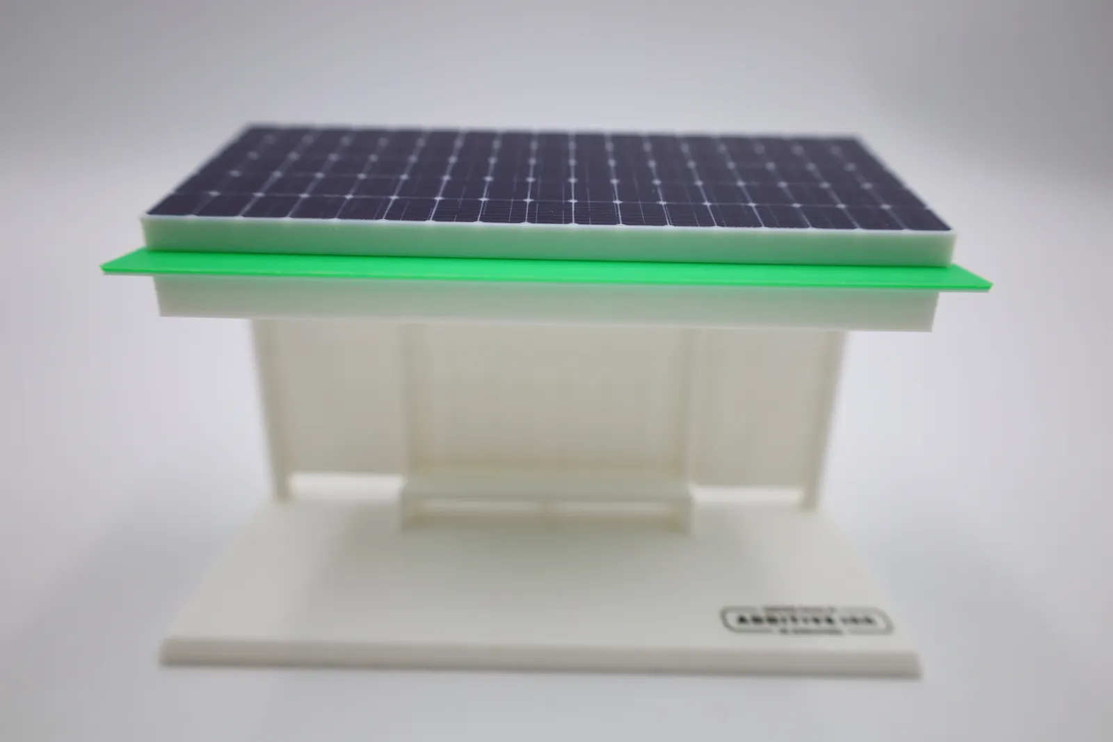 The finished model face on: solar panel roof, green roof plate, white walls and bench on a white base