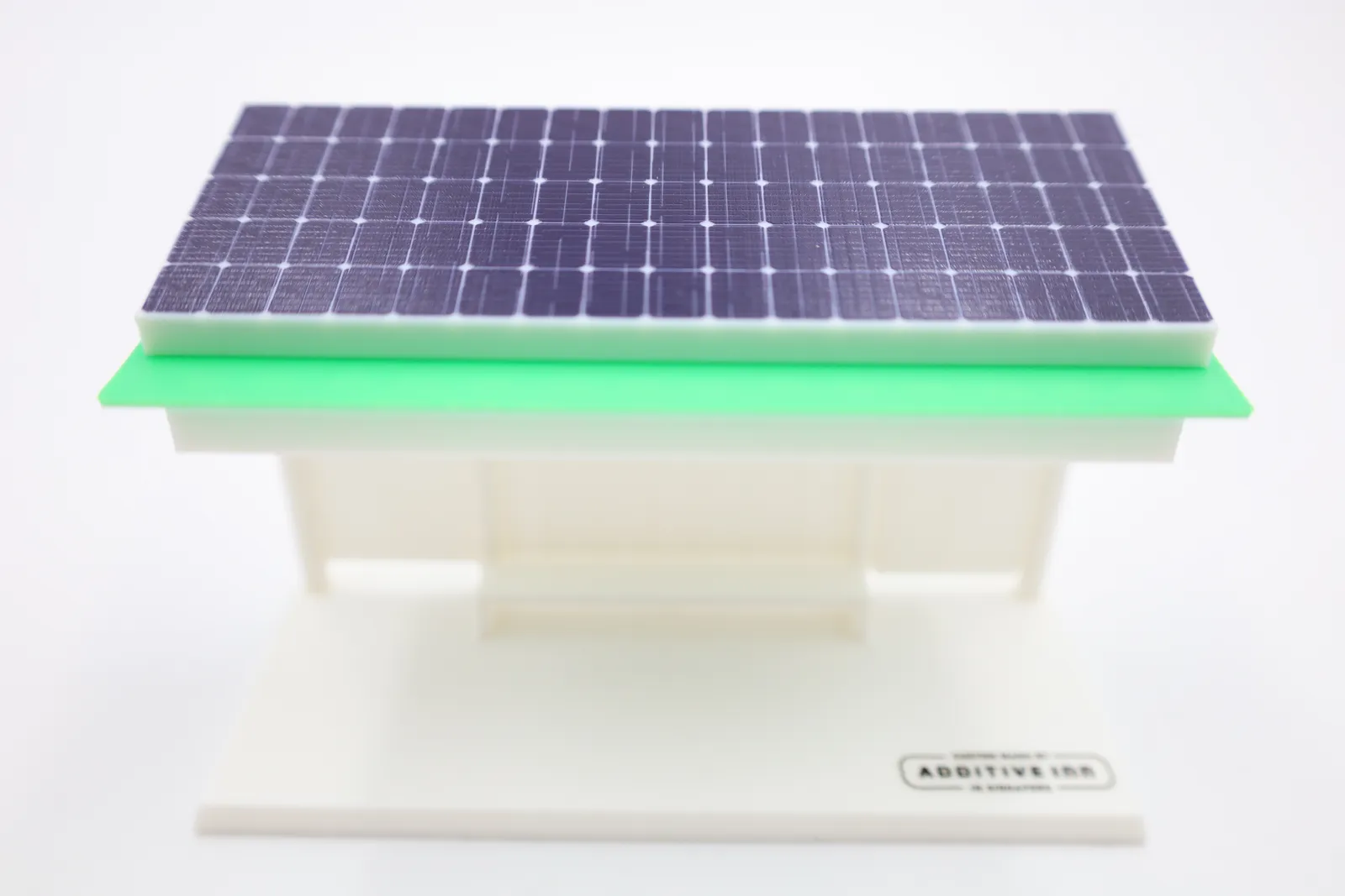 The roof from the front: a grid of dark blue solar cells printed on a white block, sitting on a bright green roof plate