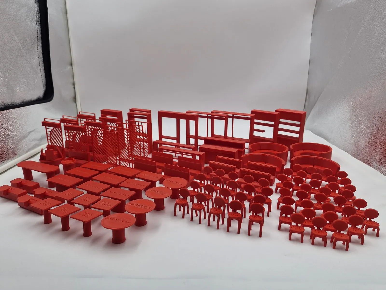 A full front-of-house set in red: booth tables, square tables, rows of chairs, round booth seats, shelving and divider screens, all at 1:25 scale
