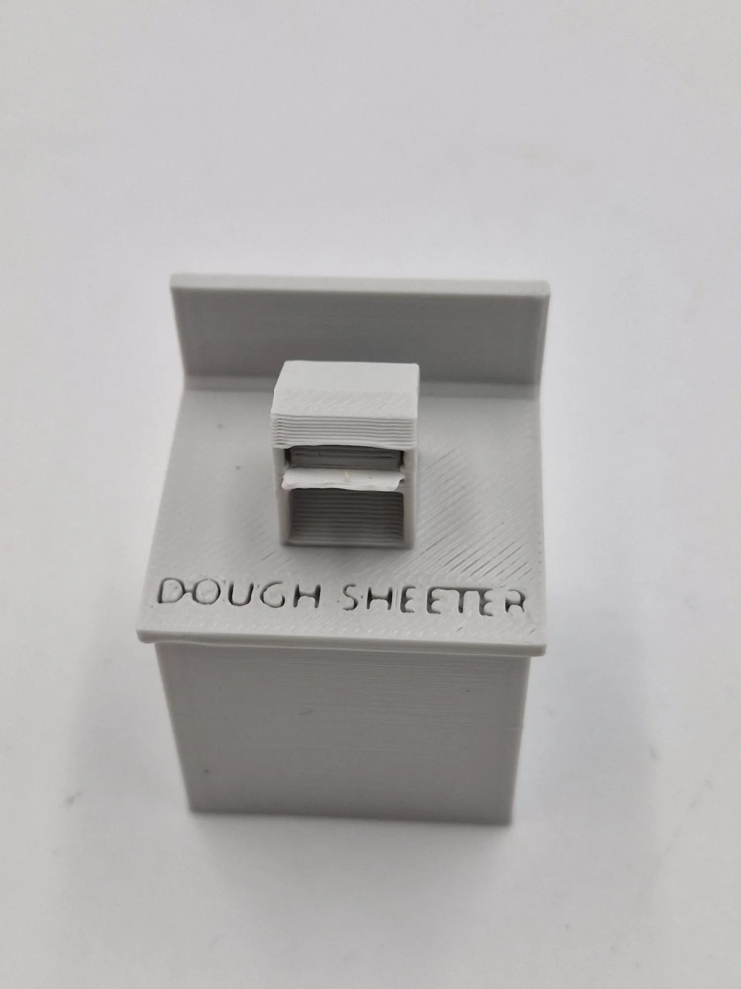 The modified dough sheeter: a grey counter with a small sheeter machine on top and DOUGH SHEETER printed on the front edge