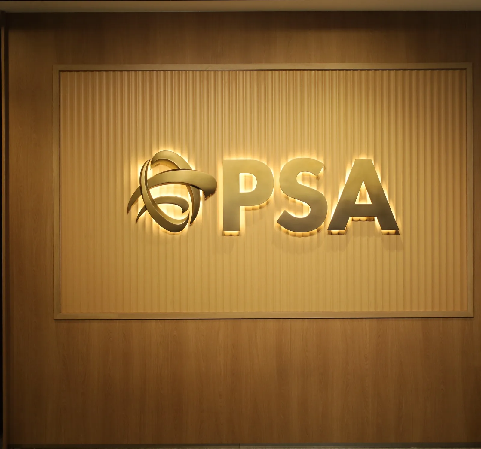 The finished PSA sign seen head-on through the office doorway, glowing on its fluted wooden panel