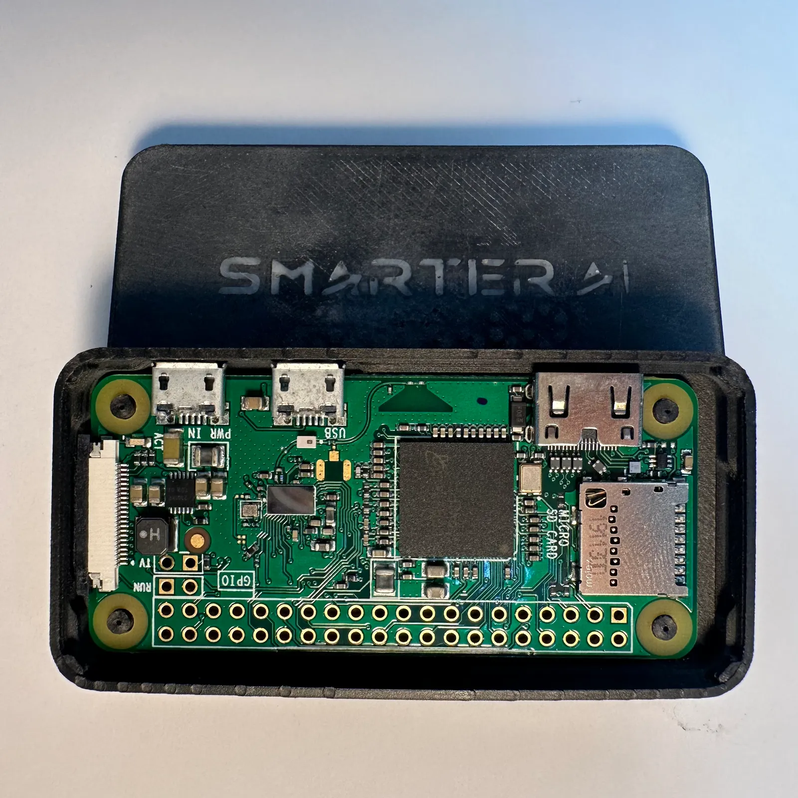 The open case holding the Raspberry Pi Zero in front of its lid, with SMARTER AI lettered in grey across the black lid