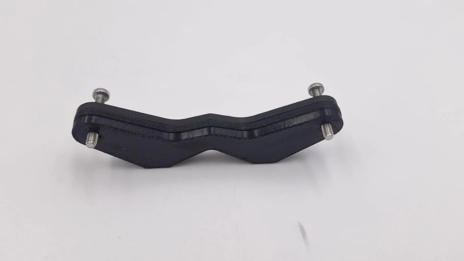 The finished zigzag bumper bracket, its black plates stacked and bolted together with a steel screw at each end