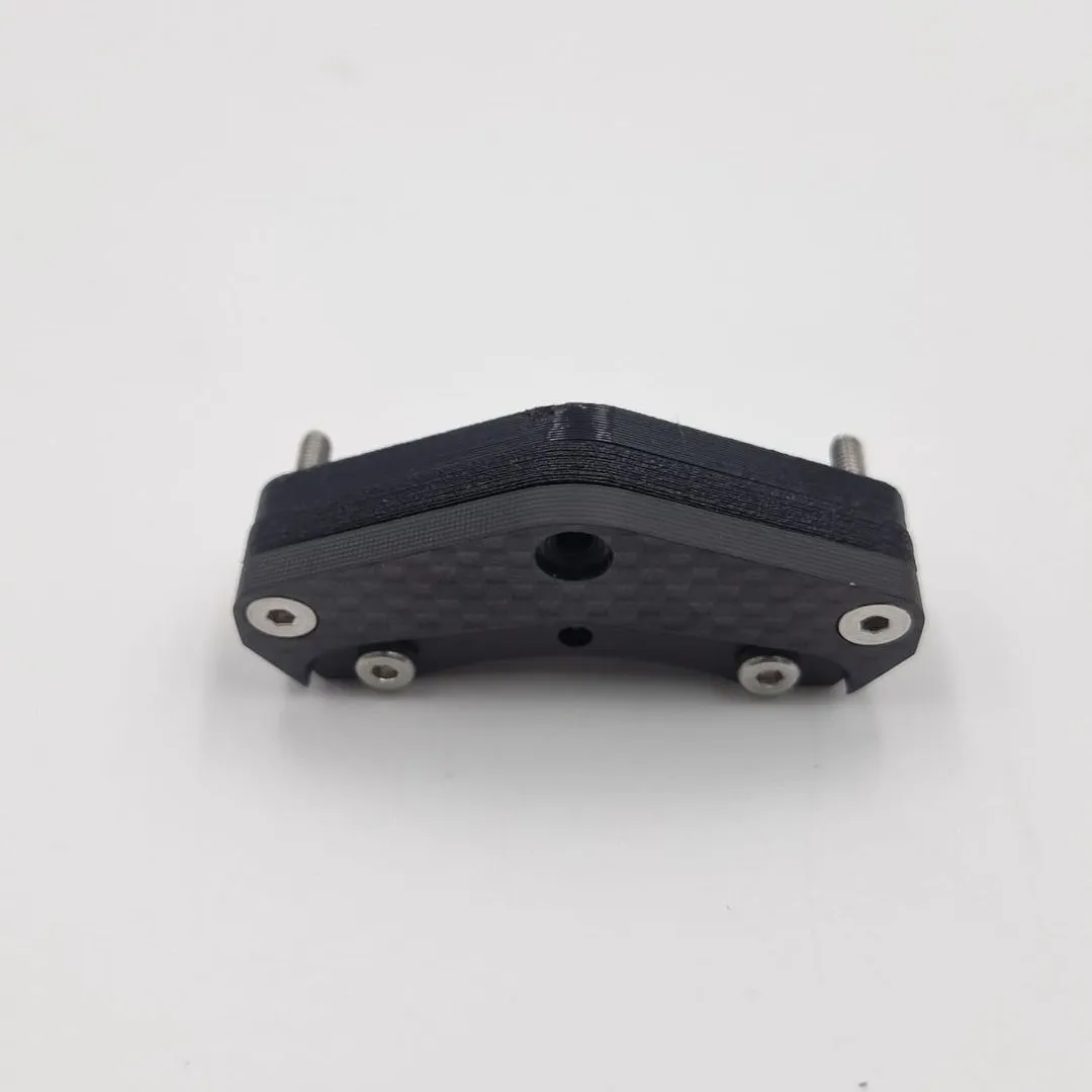 The underside of the four-stud bracket, a carbon fibre face with four steel screw heads and a centre hole, the printed layers above it