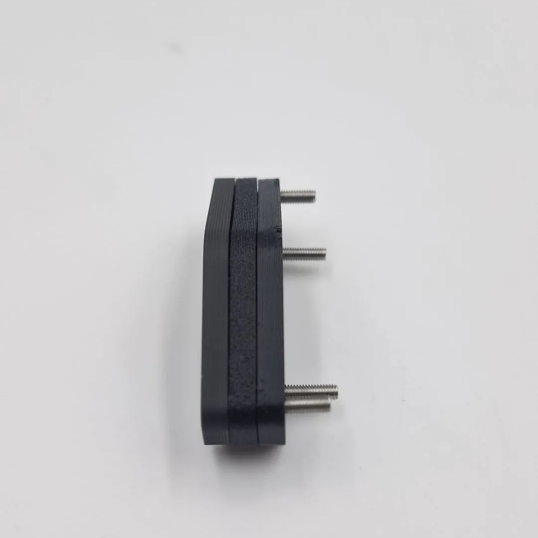 The four-stud bracket seen edge on, the printed layers sitting flat against each other and the steel studs sticking out to one side