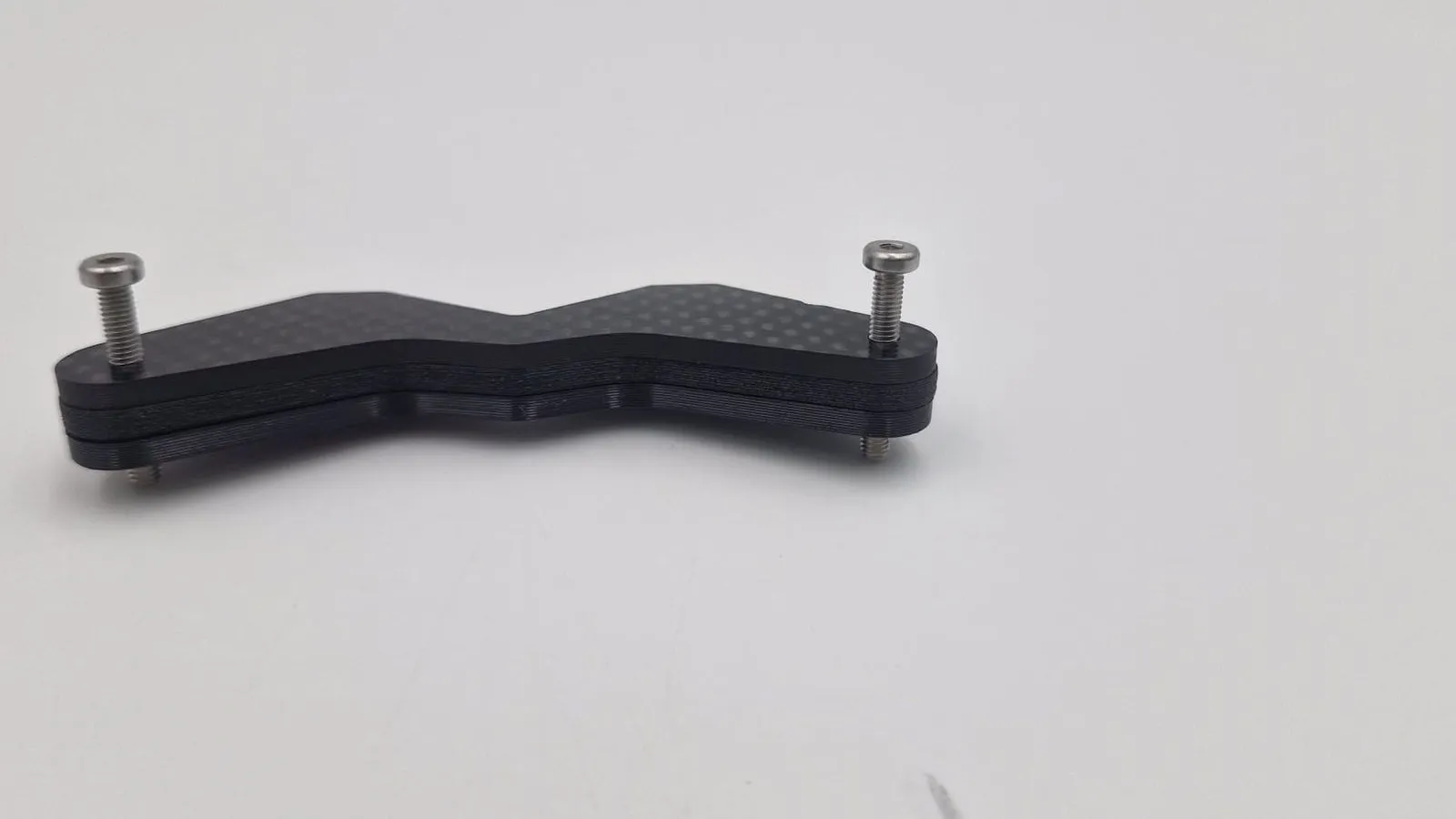 The zigzag bracket from above, its plates stacked and held by a steel screw at each end