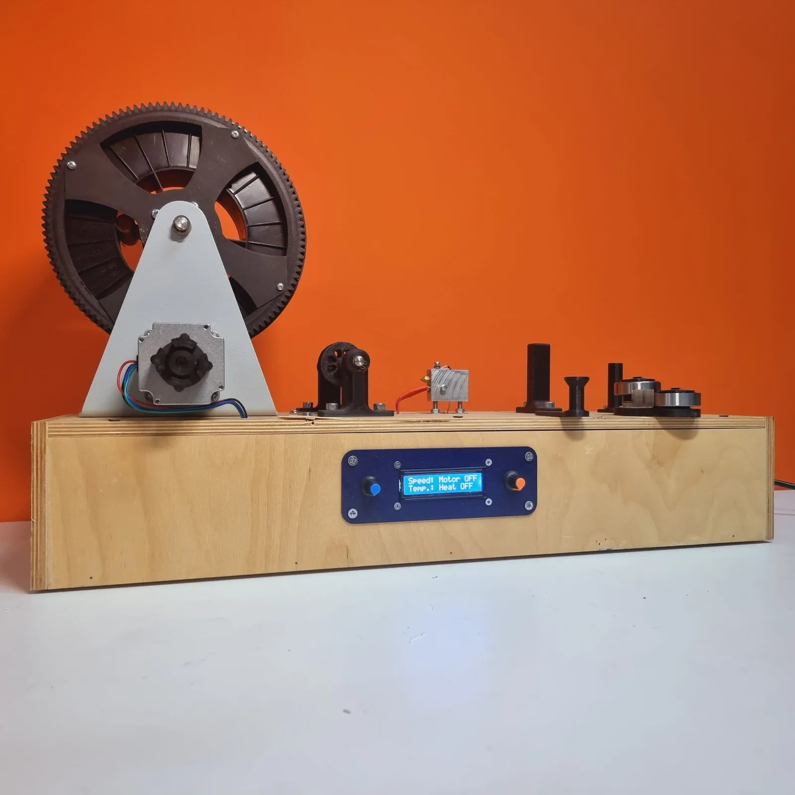 The rig from a front corner, its blue front panel showing a lit display that reads speed and temperature between two dials