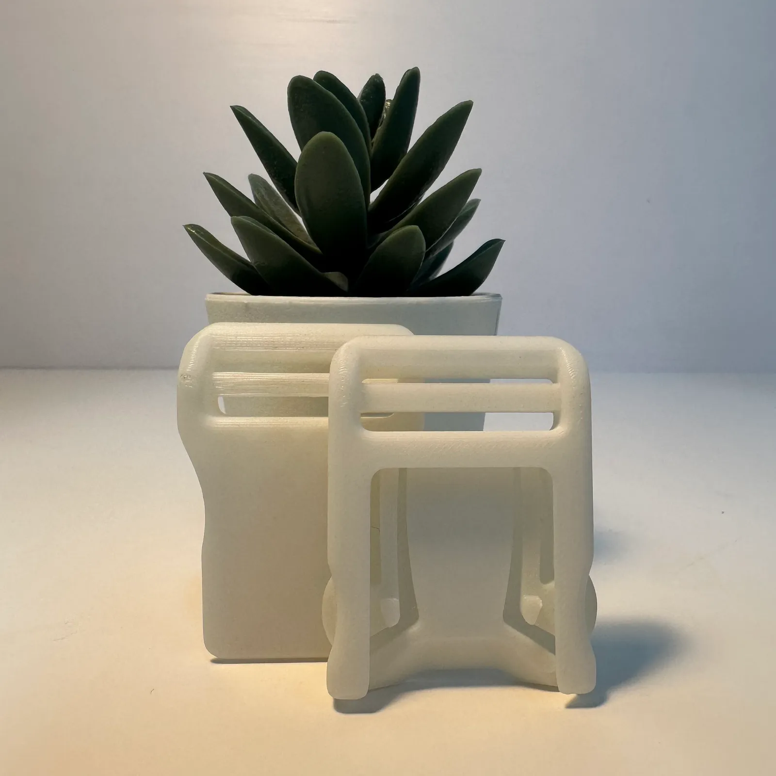 The two halves standing upright, the clip in front of the socket, on a white table beside a small potted plant