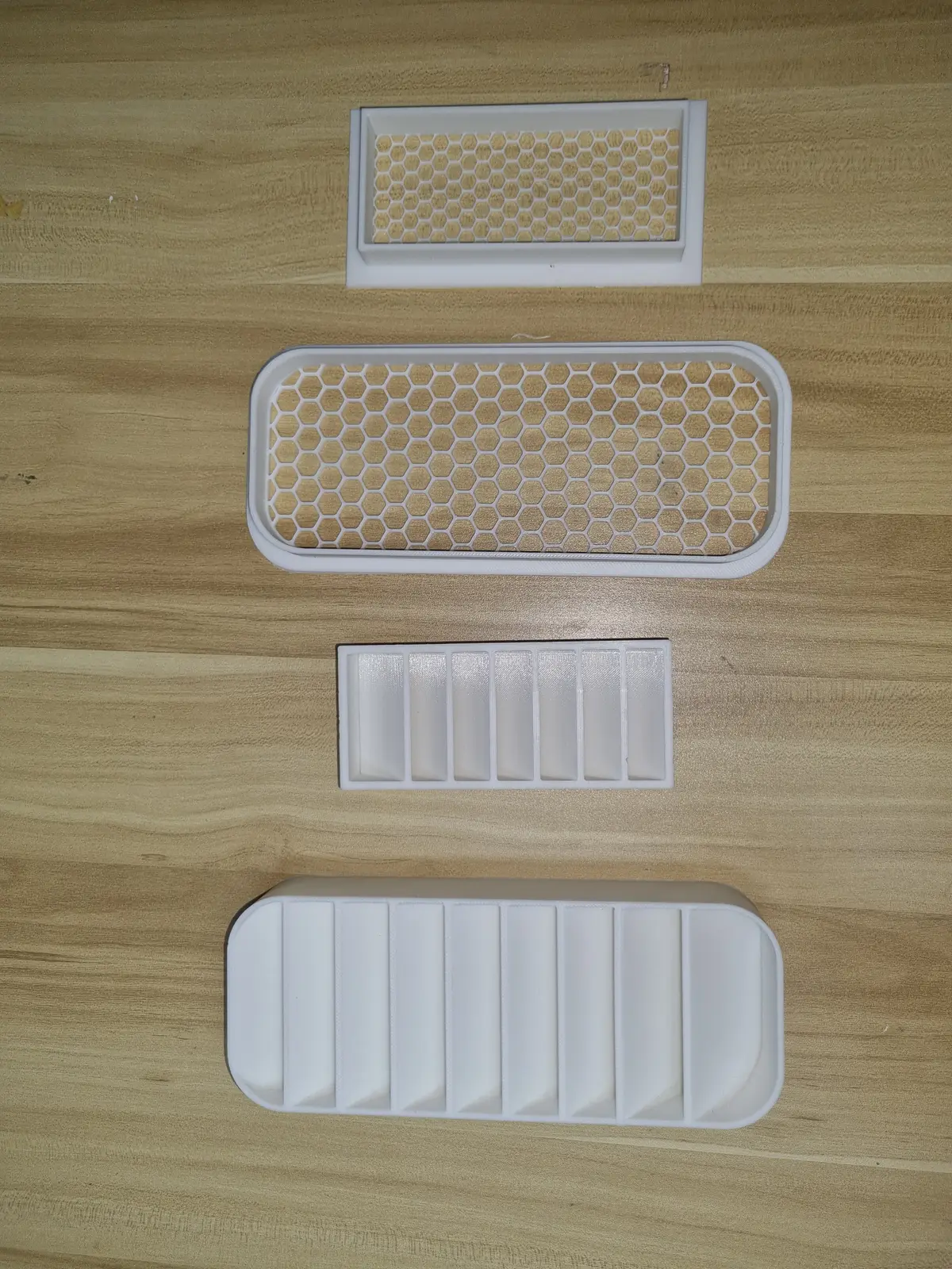 The client's four original vent samples on a wooden table, with the large vent still in its honeycomb design