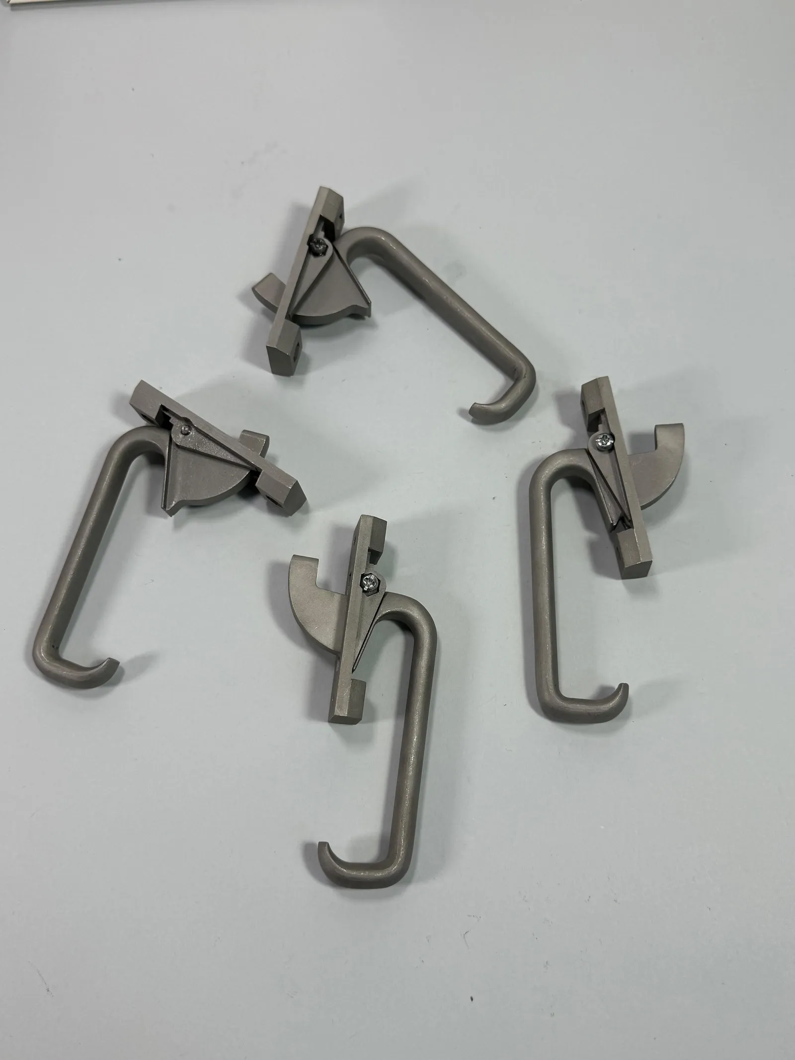Top-down view of the four finished latches laid flat, showing the full length of each hooked handle and the shape of each catch