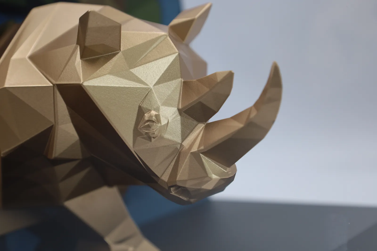 Close-up of the gold rhino's faceted head and curved horn