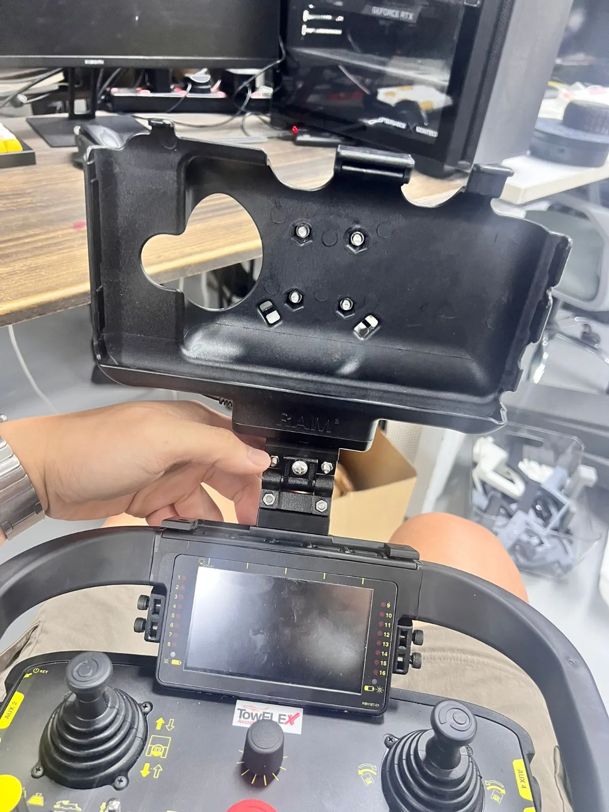 A hand fitting the tablet cradle onto the black mount above the remote controller's screen, its joysticks below