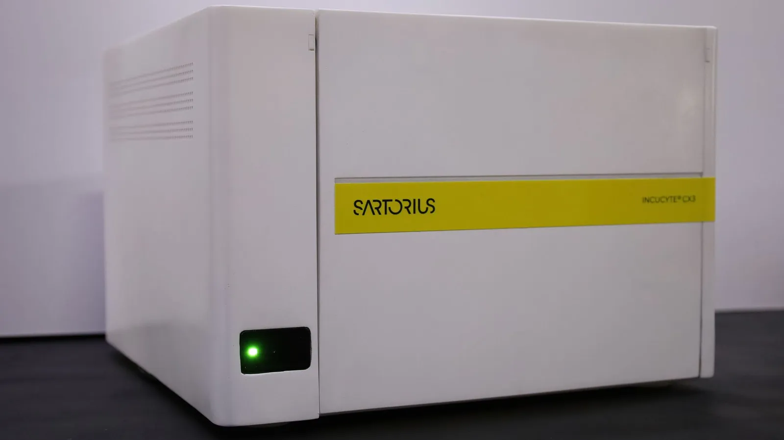 The Incucyte CX3 model closed, a white box with the yellow Sartorius band across the front and a green status light at the lower left
