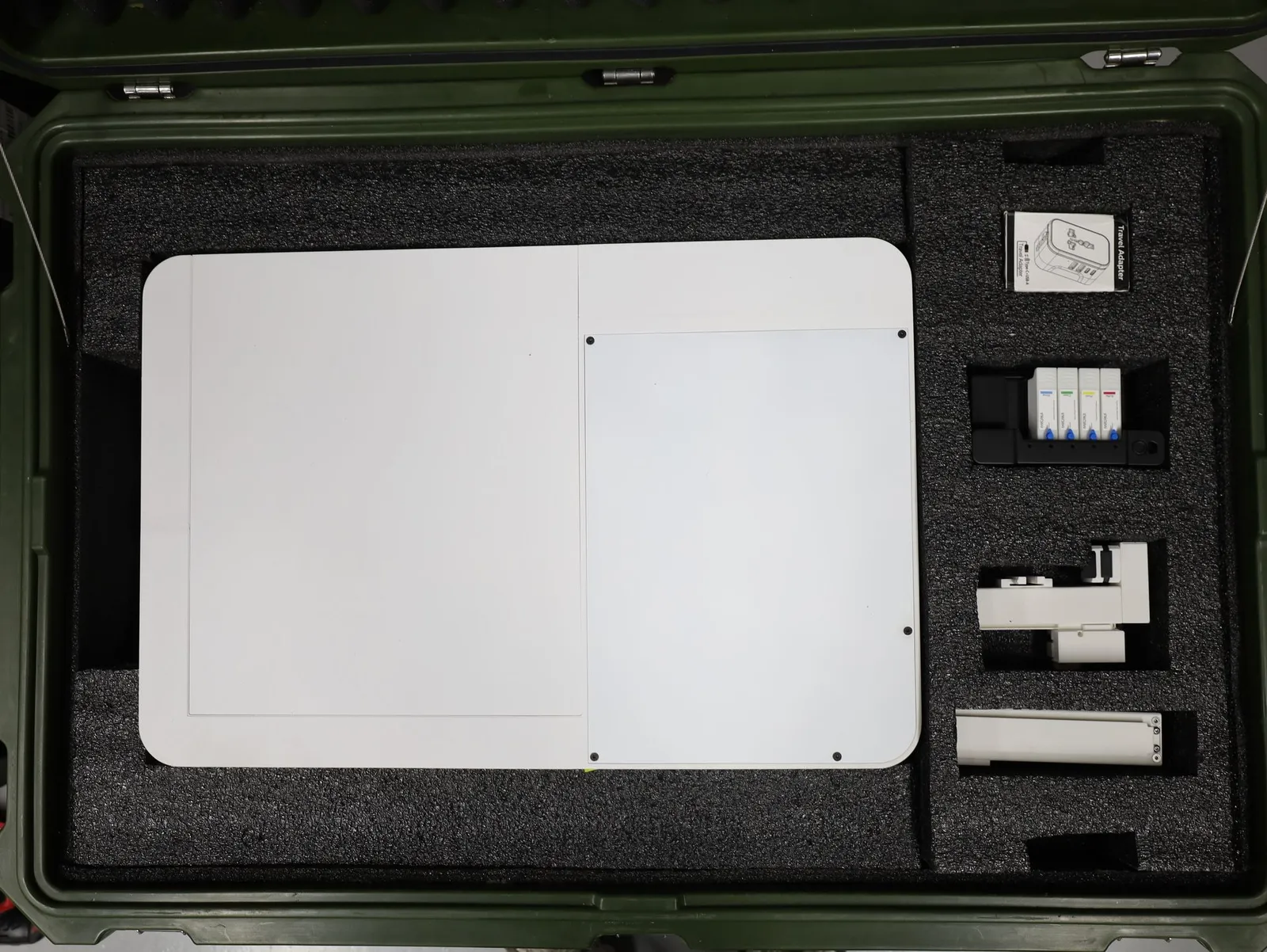 A hard case lined with dark foam holding a large white panel and small white and black parts, each in its own cut-out