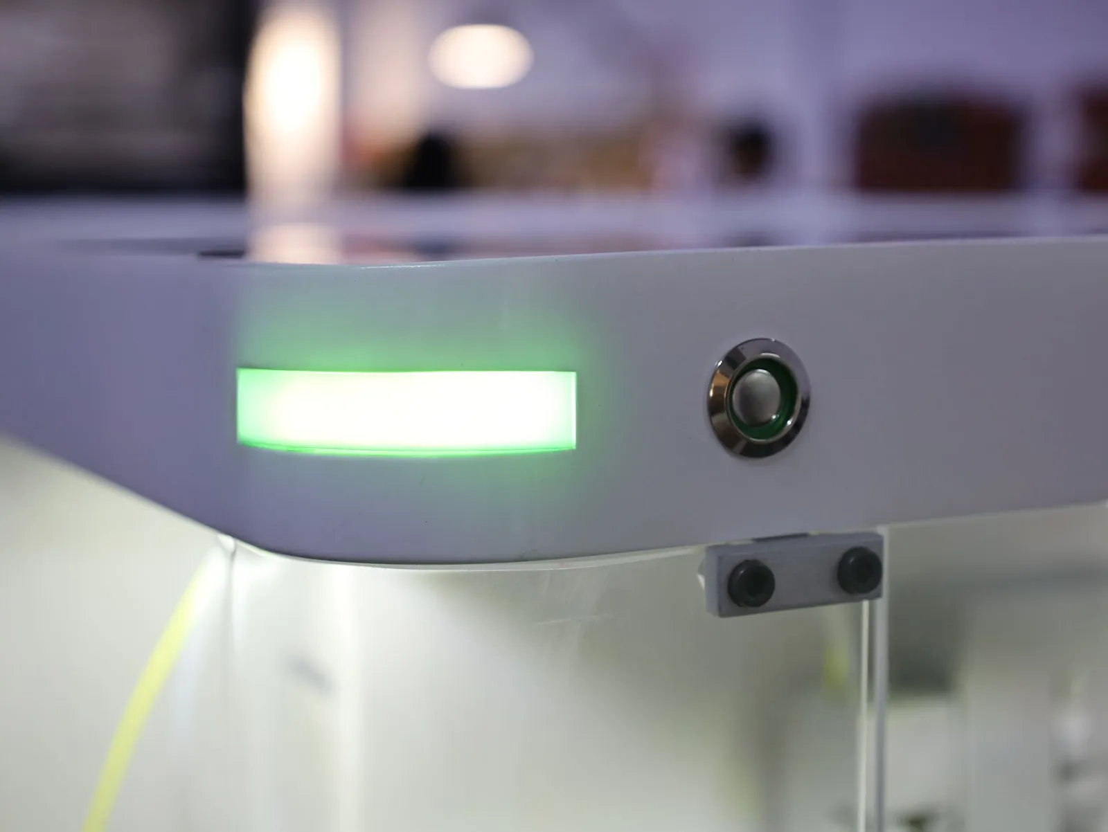 The green light bar along the top edge of the iQue 5 model, lit, with a round metal push button beside it