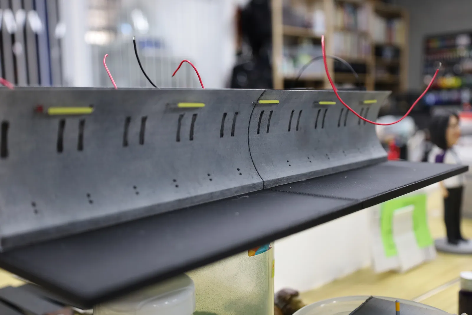 A painted tunnel wall on the workbench with small lights fitted along its top and red wires trailing behind