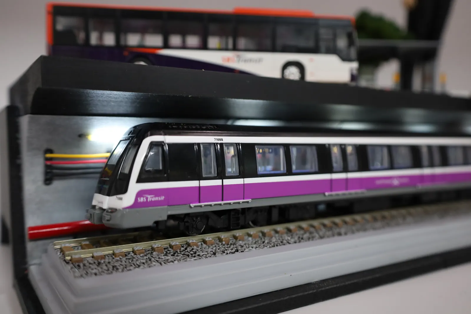 The MRT train lit from above under the road deck, running on its track along the tunnel
