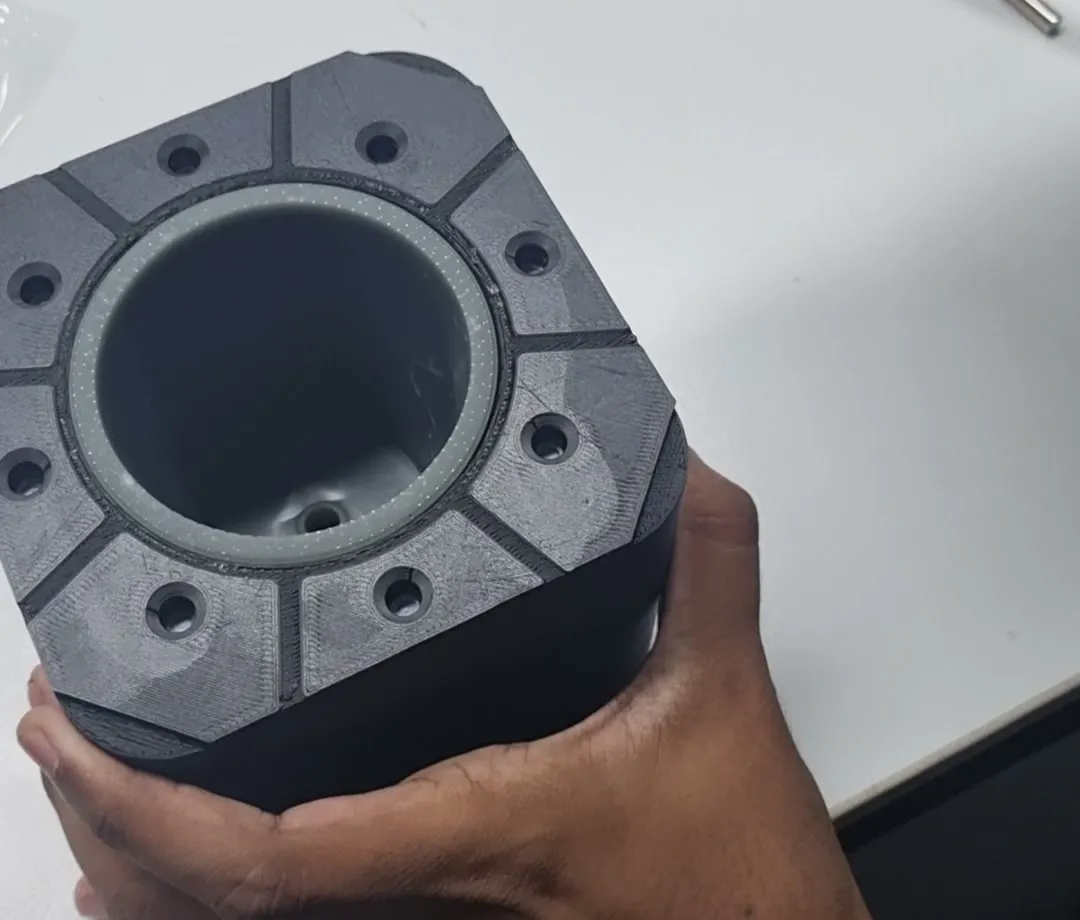 The cup mould opened, held in a hand: the printed black plate ringed with bolt holes around a smooth grey resin cavity insert