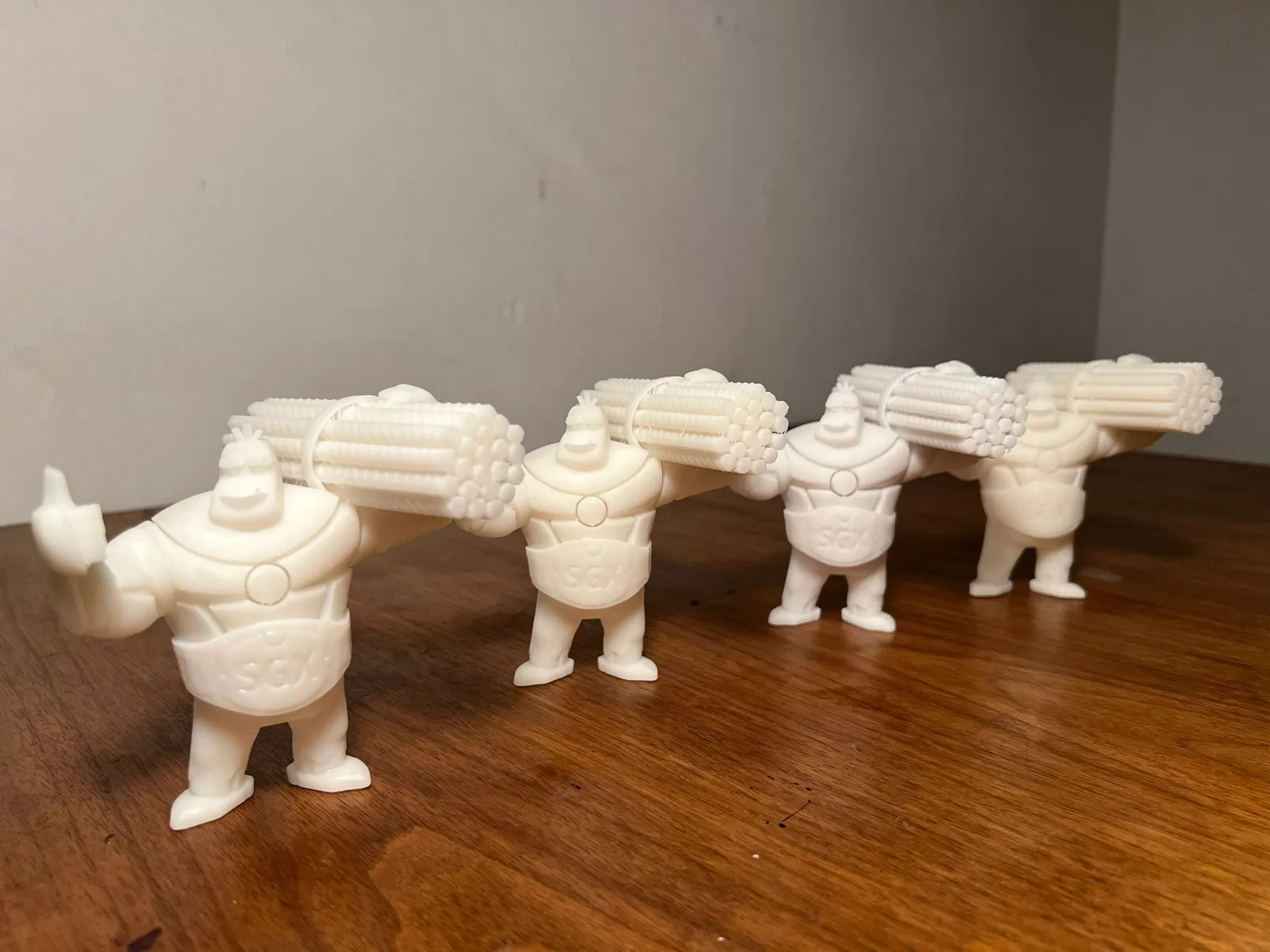 Four white printed mascot figures standing in a row, each giving a thumbs-up with rebar on his shoulder