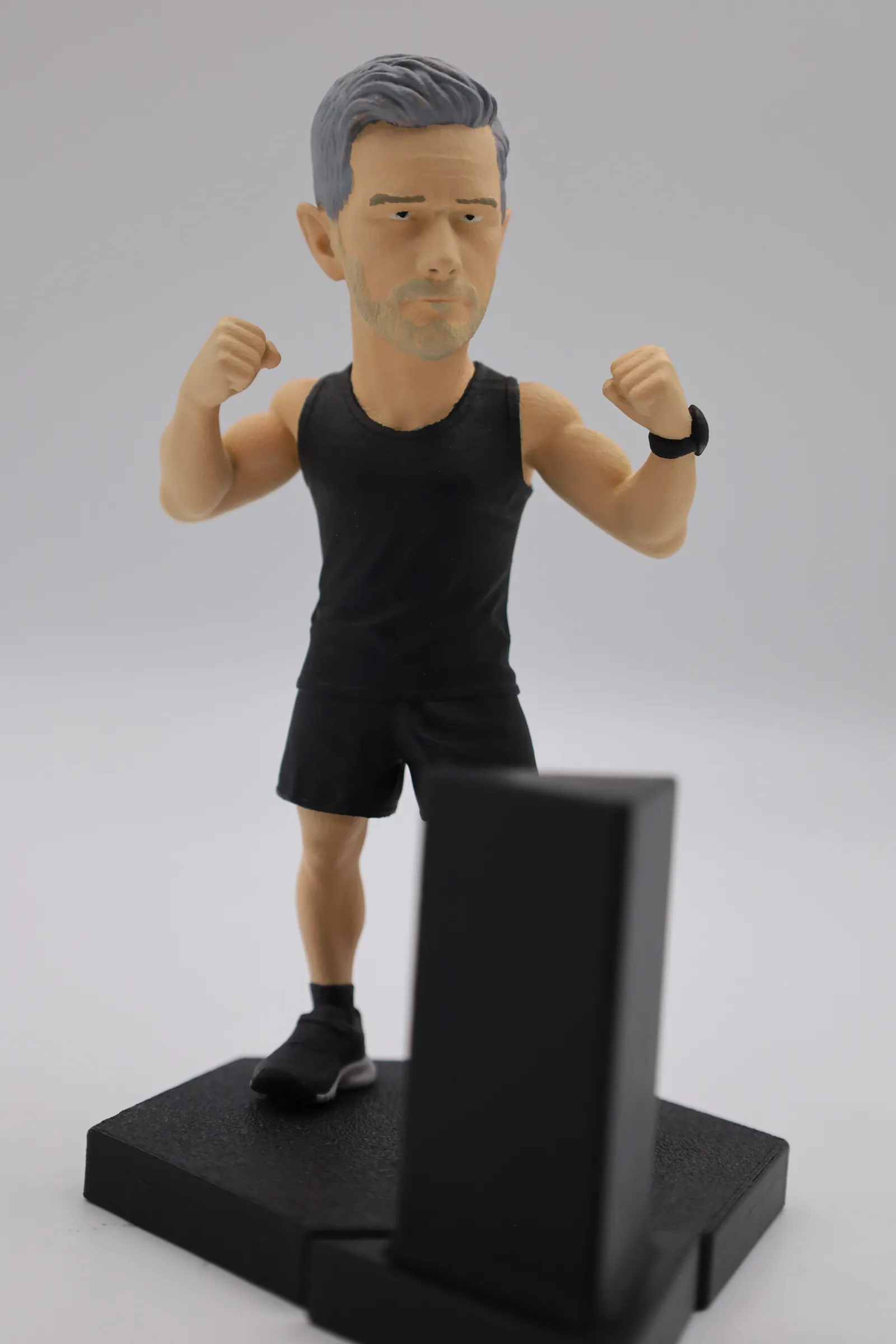 The finished 150 mm figure in a black vest and shorts, fists raised, standing on a black hexagon base with a raised back panel