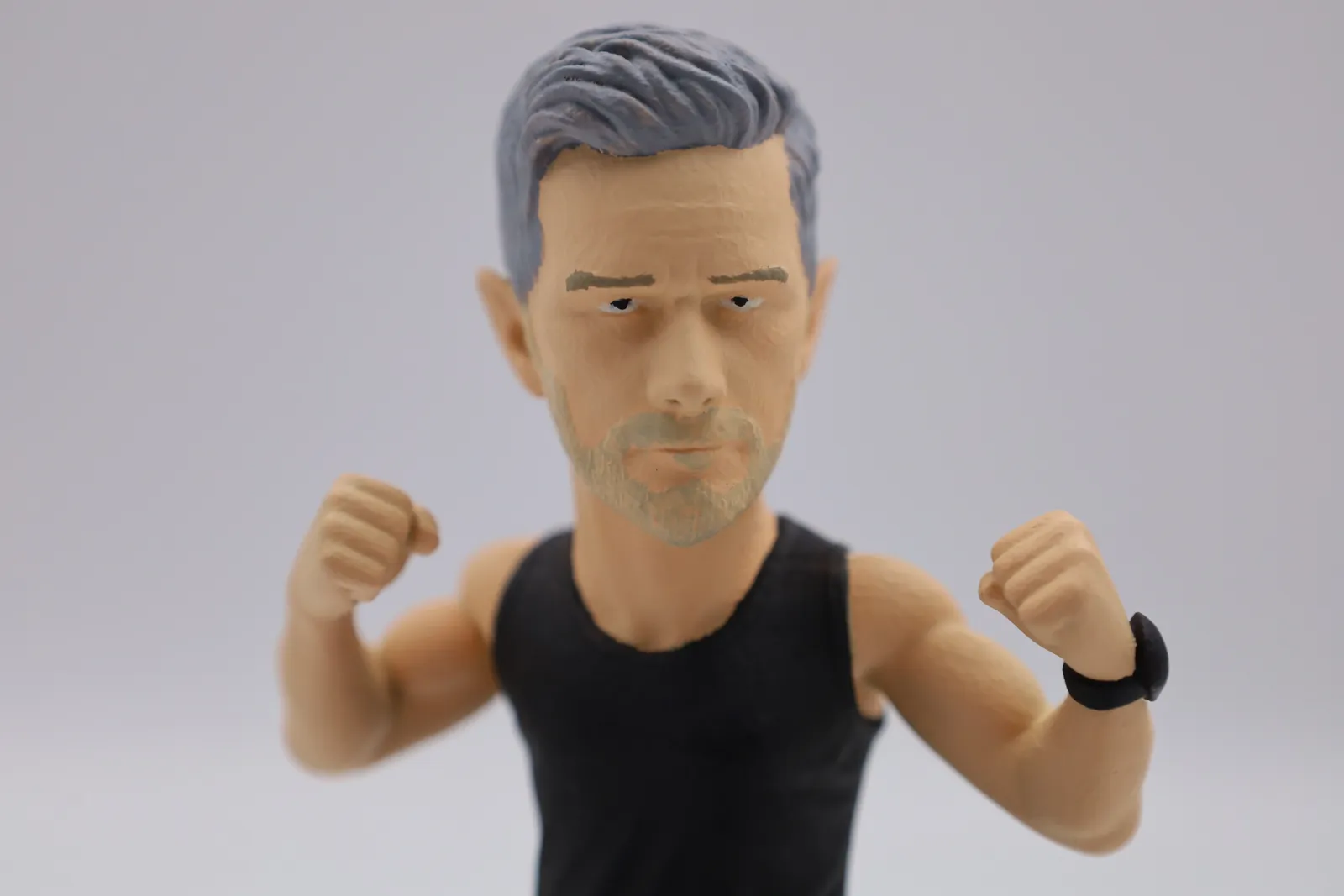 Close up of the painted face: grey hair, light stubble, painted eyebrows and eyes, and a black watch on one wrist