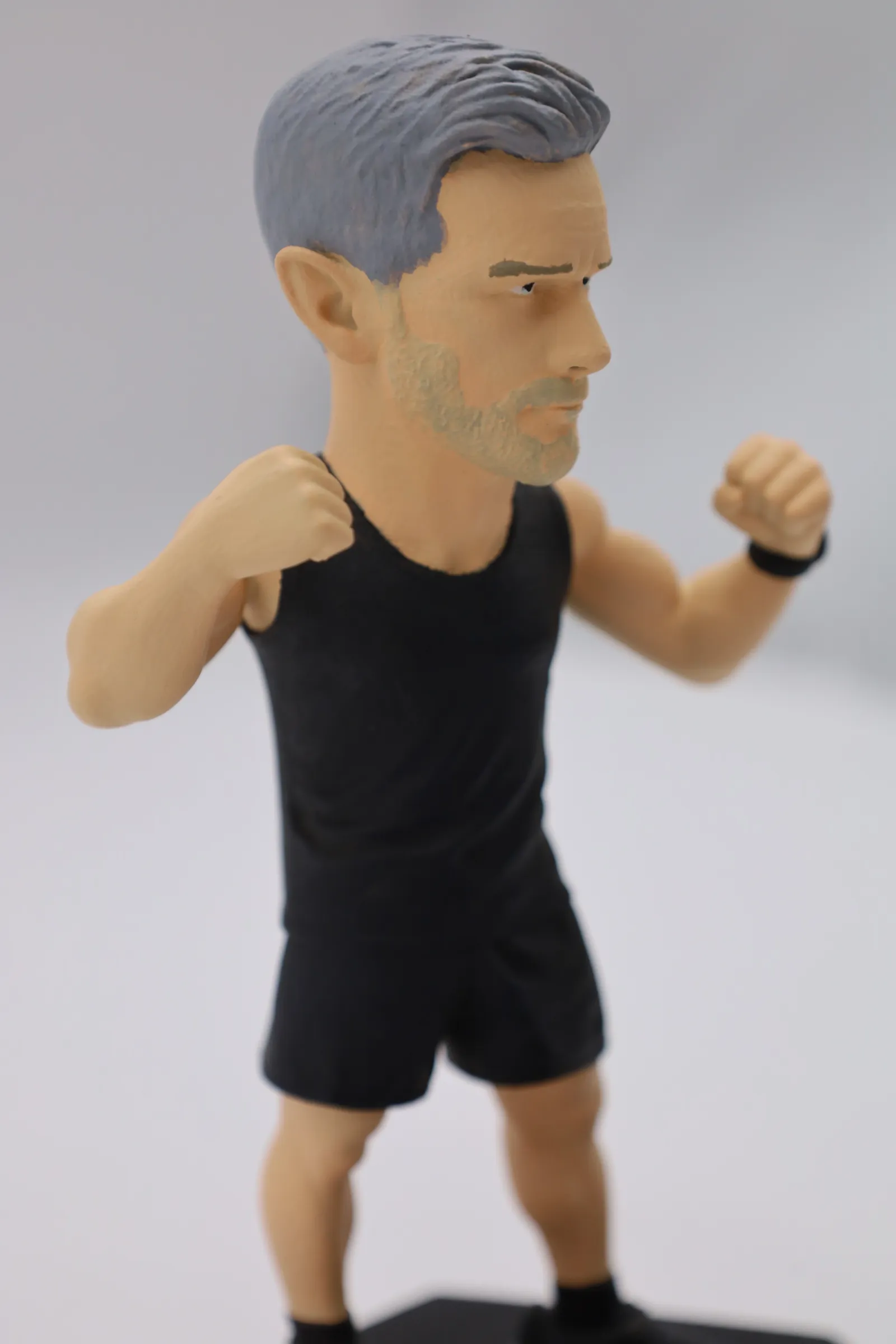 Three-quarter view of the painted figure, showing the sculpted hair and the texture of the black vest