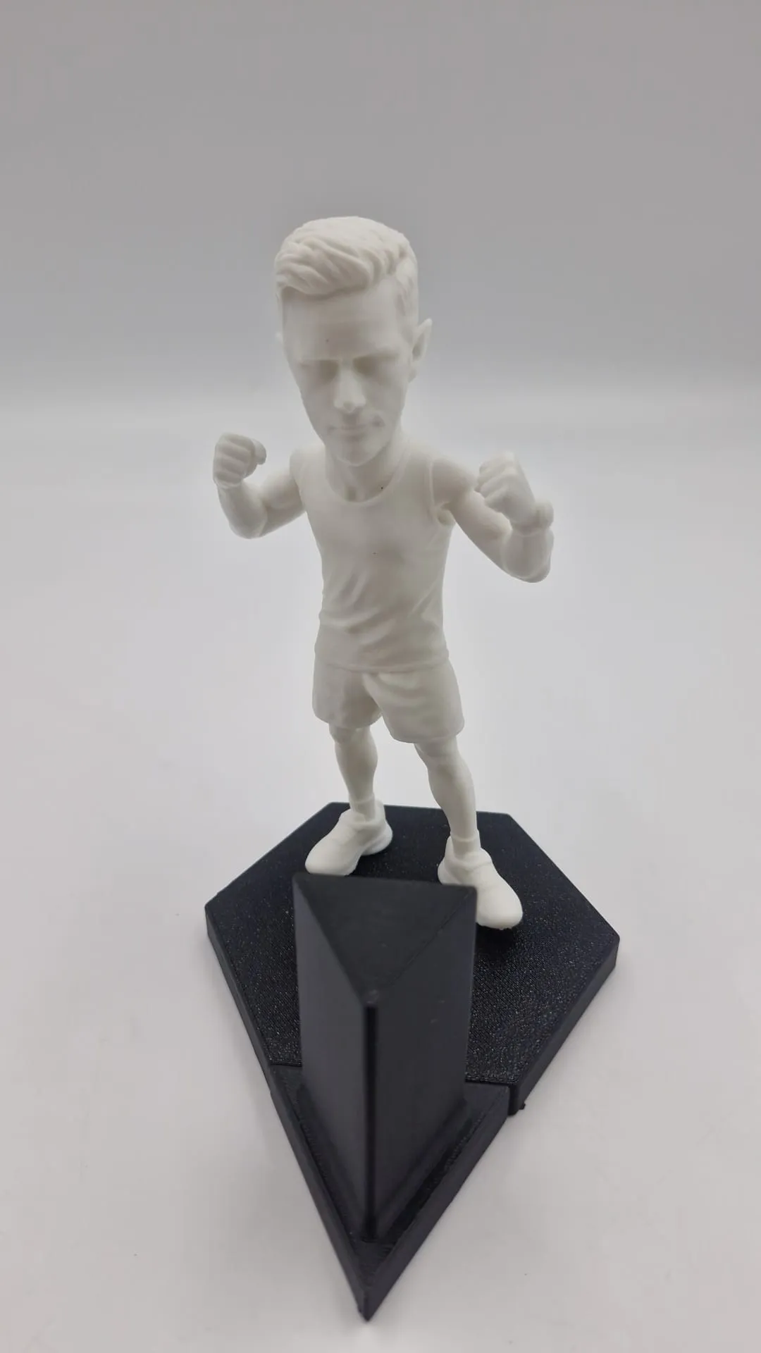 The figure straight off the printer in white resin, standing on the black base with its raised back panel