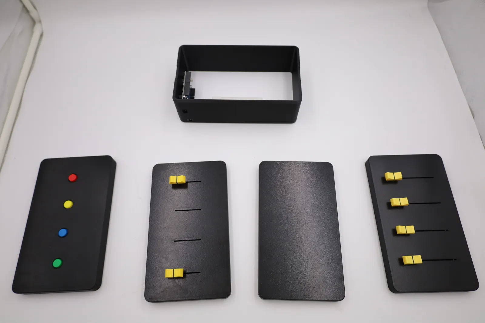 Every part of the response box laid out: the open body, the push-button lid, the long-slider lid, the plain bottom lid and the short-slider lid