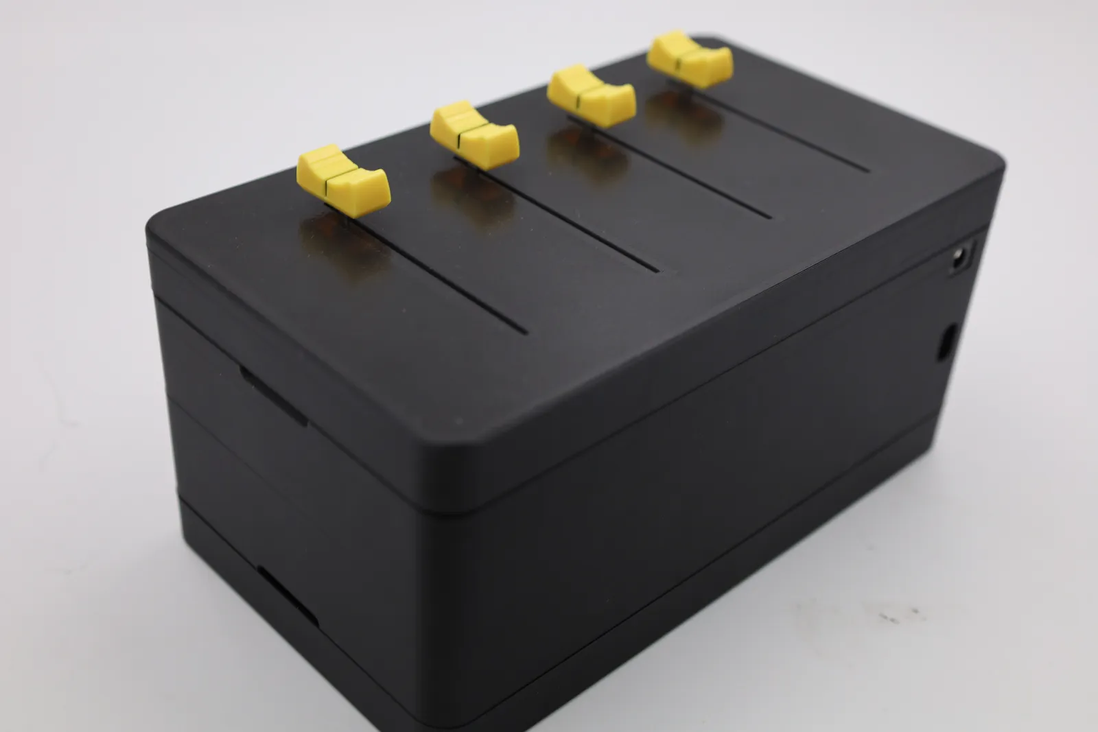 The box with the short-slider lid fitted: four yellow slider knobs side by side, each in its own slot