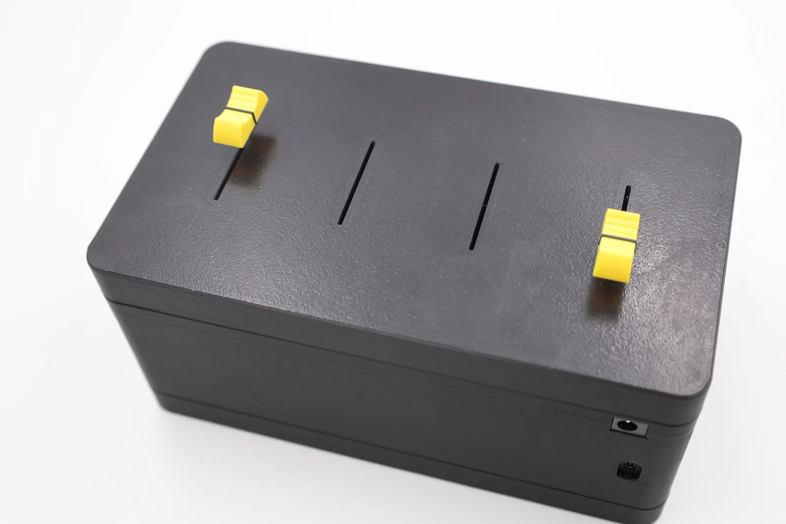 Top view of the long-slider lid on the box, with four long slots and two yellow slider knobs fitted