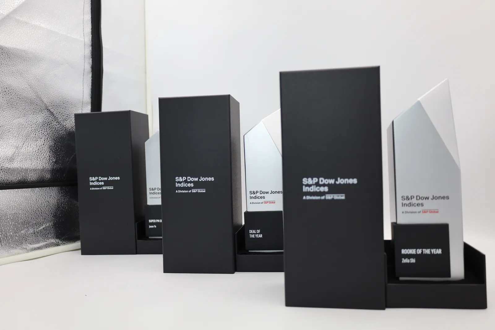 The black gift boxes, lids printed with the S&P Dow Jones Indices logo, in front of the finished trophies