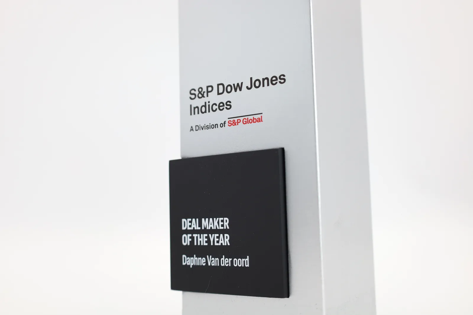 Close-up of the S&P Dow Jones Indices logo on the silver column above a black plate reading DEAL MAKER OF THE YEAR, Daphne Van der oord