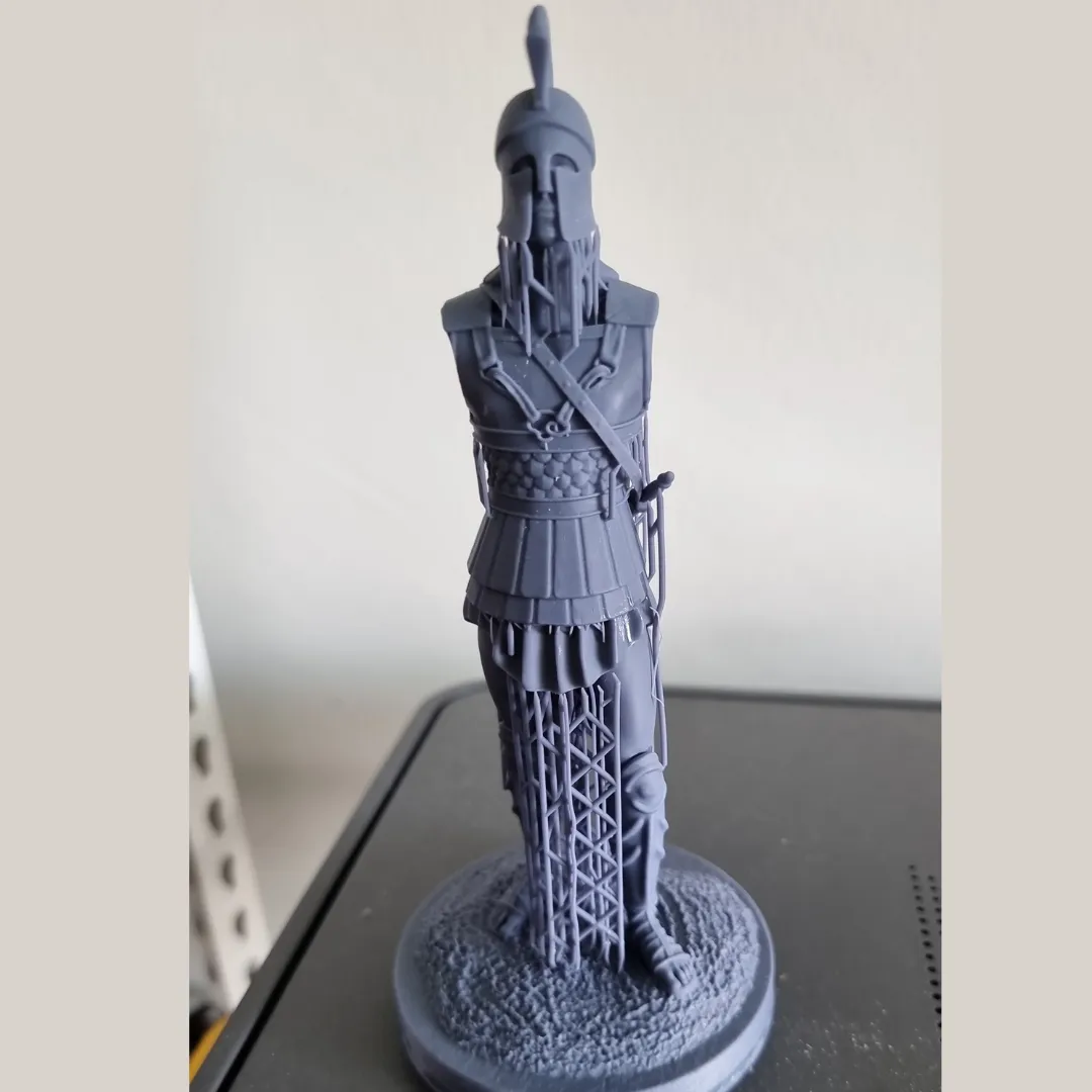 The back of the raw grey resin Spartan print, showing the lattice supports between the legs and the textured base