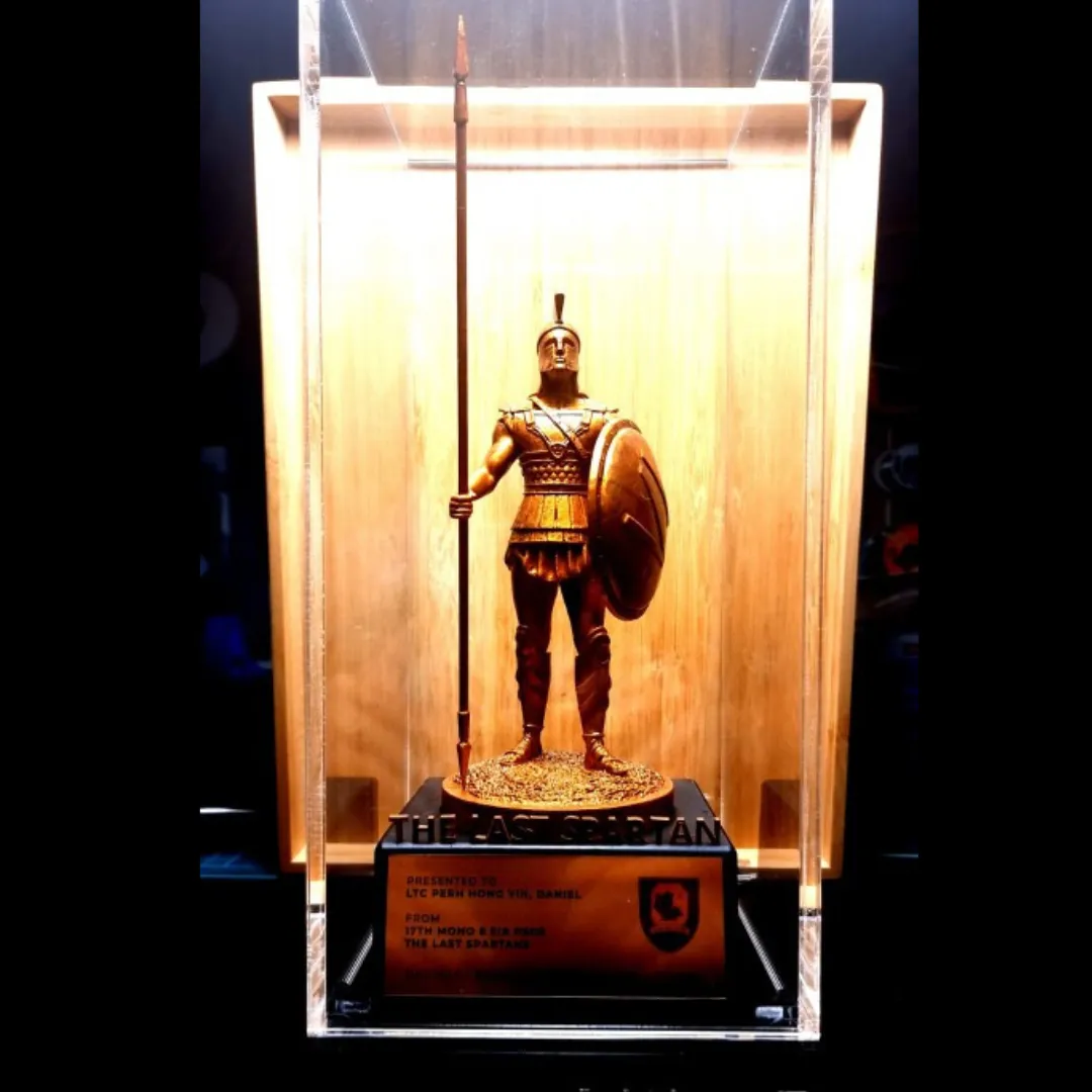 A Spartan trophy in a clear acrylic case, lit warmly from behind