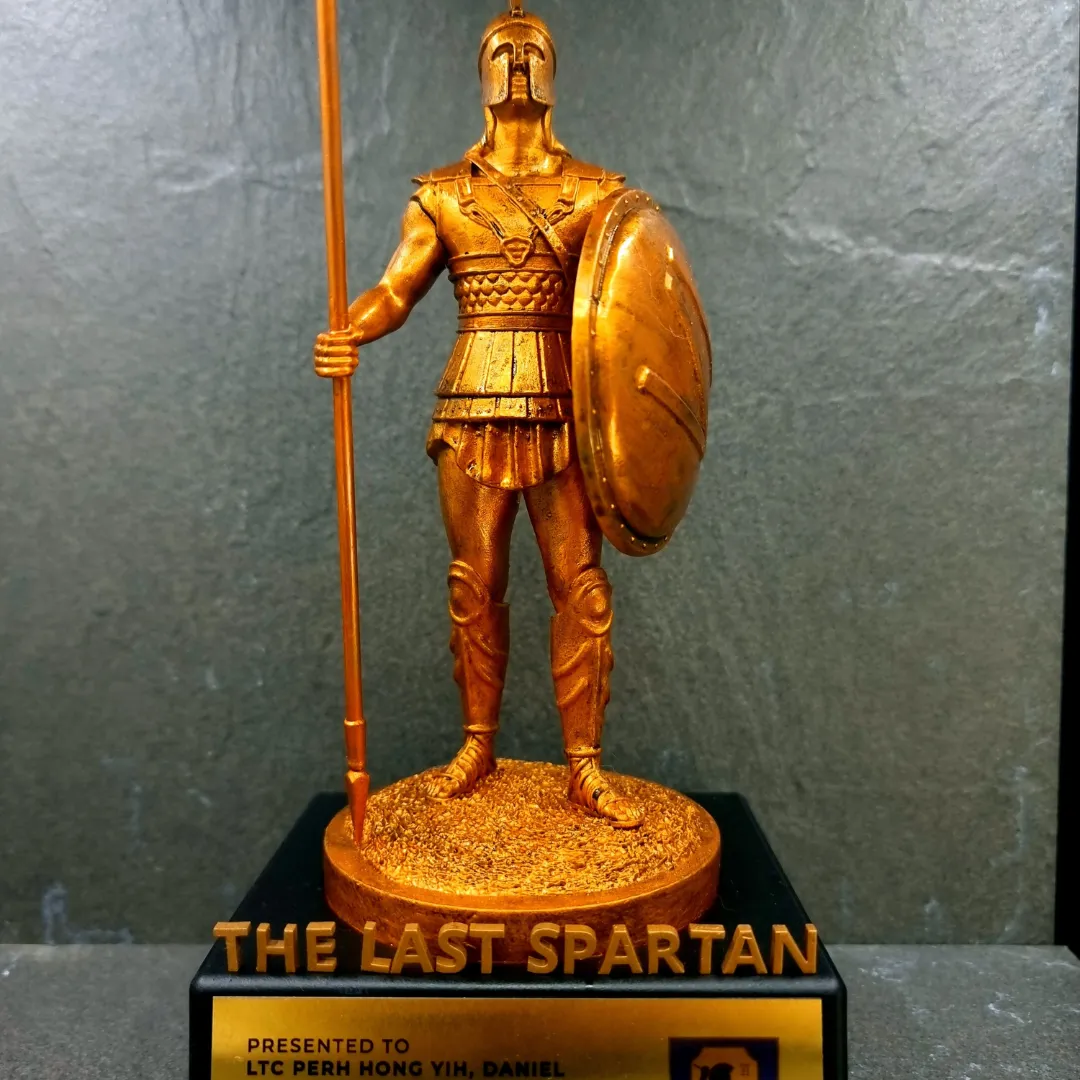 Close-up of the bronze Spartan's scale armour, pleated skirt and round shield, with the spear in his hand