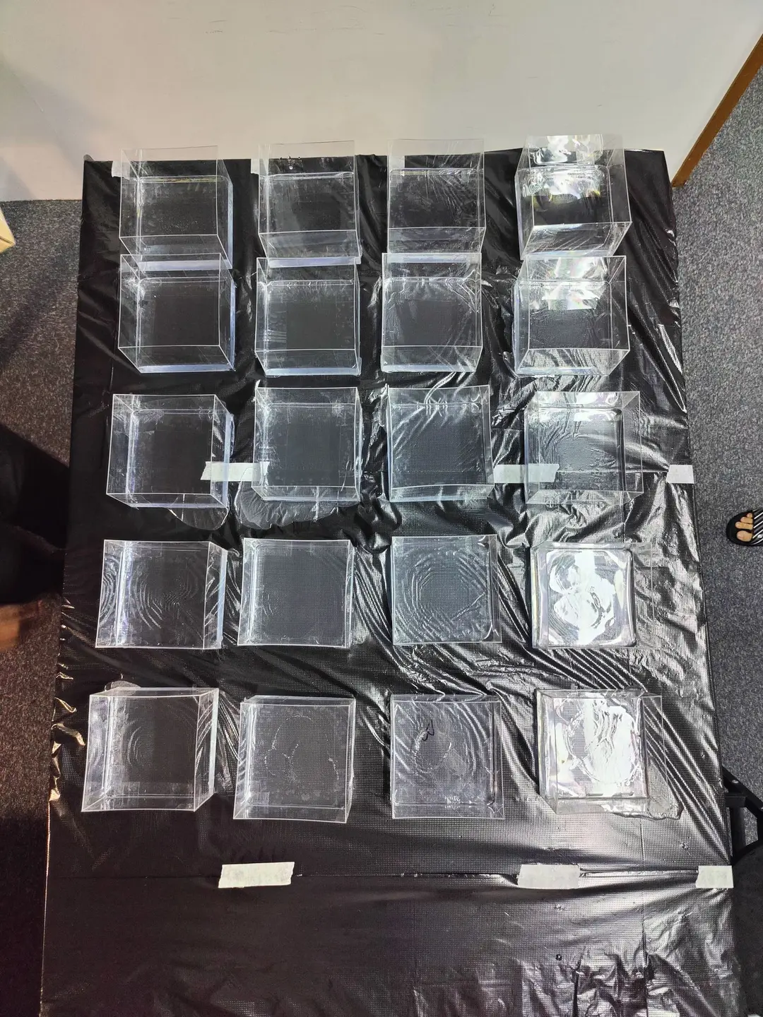 Twenty clear moulds laid out in rows on a black sheet, ready for the resin