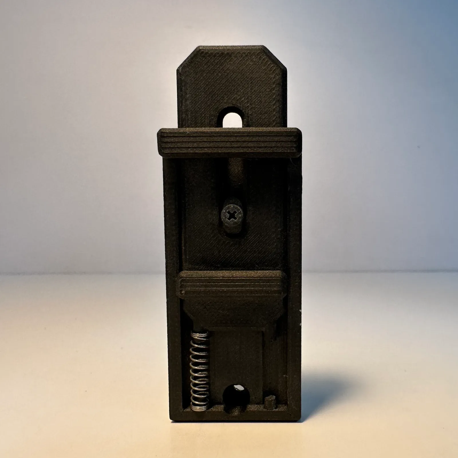 The finished rail standing upright, seen straight on: the tongue at the top, the screw, the latch grip and the spring at the bottom