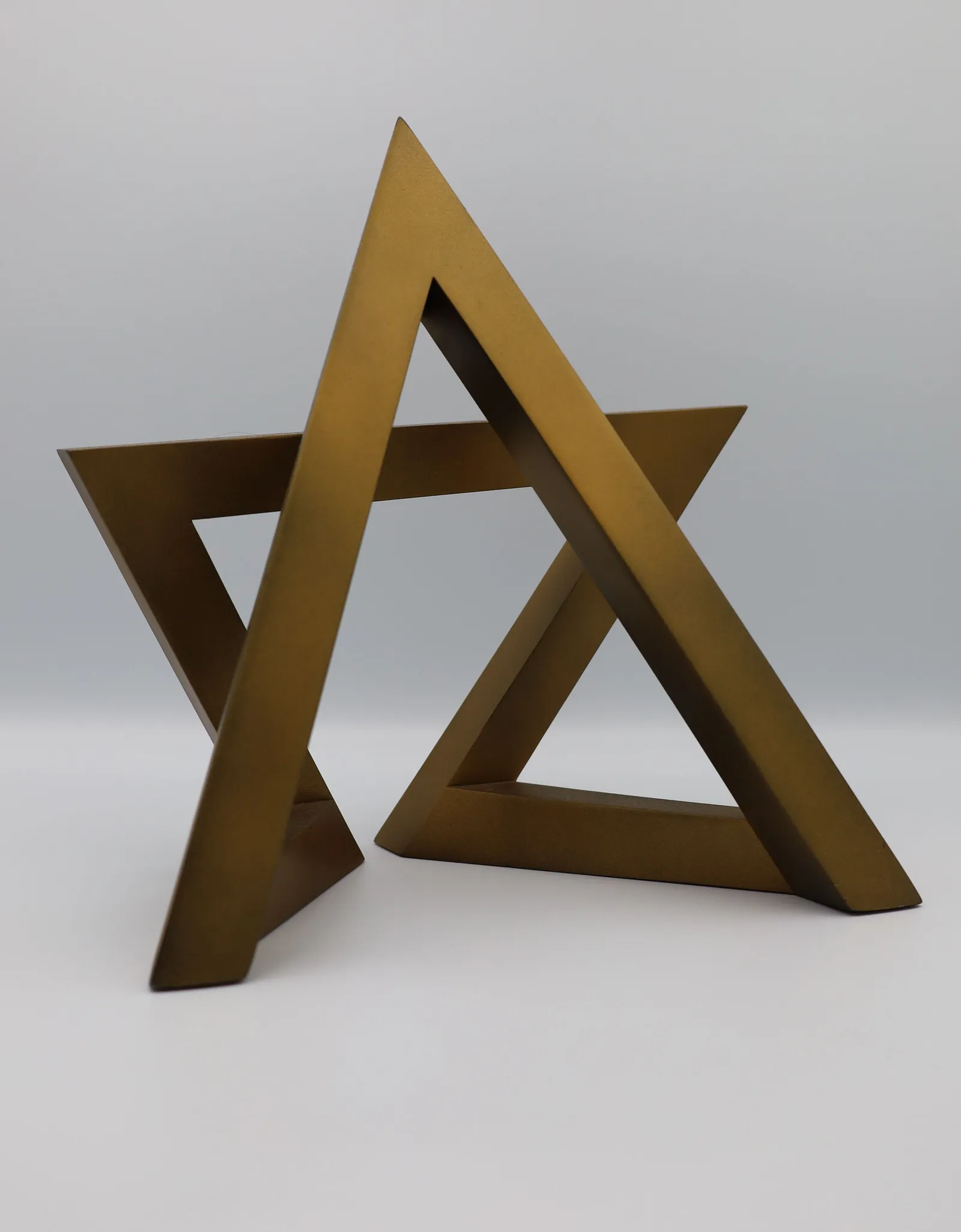 The finished gold star at an angle against a plain grey background, its two triangles interlocking