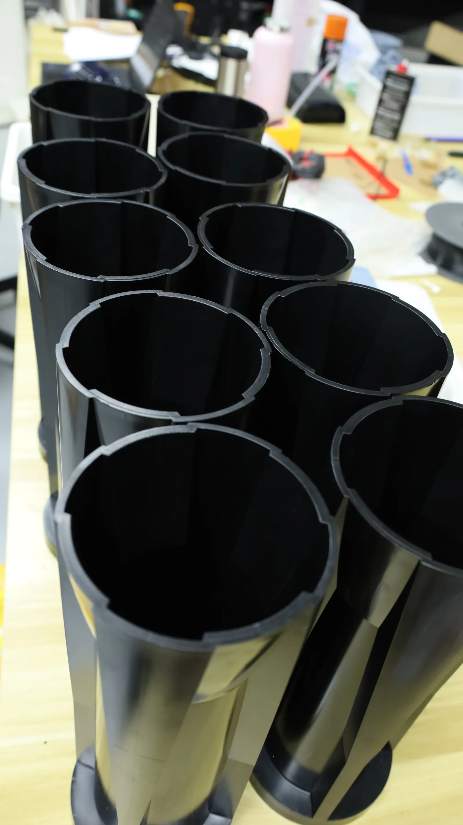 Ten moulded black sleeves standing in two rows, seen from above, their open ends showing the slots inside the rim