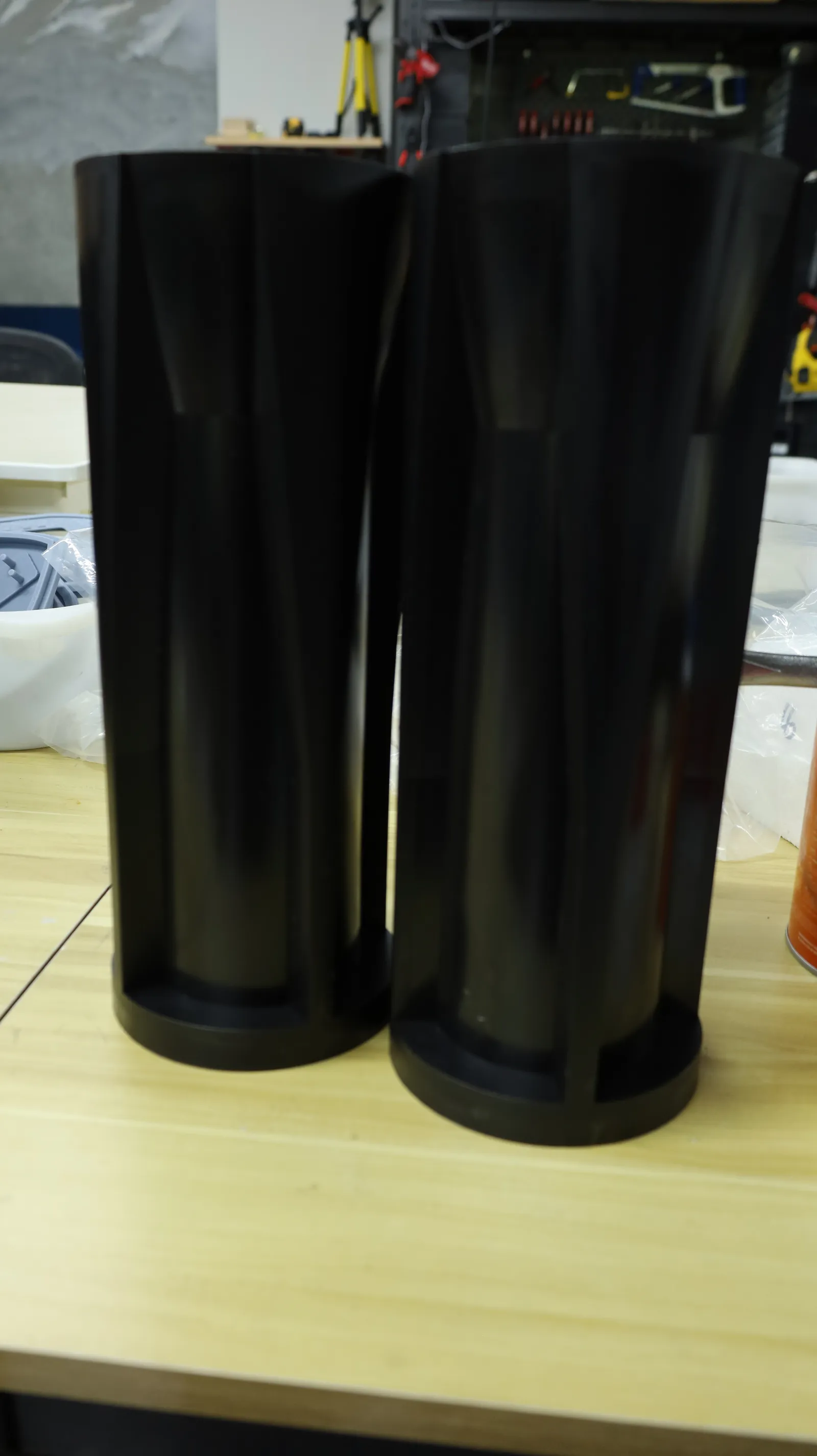 Two moulded black sleeves standing side by side on a workbench, their channels catching the light